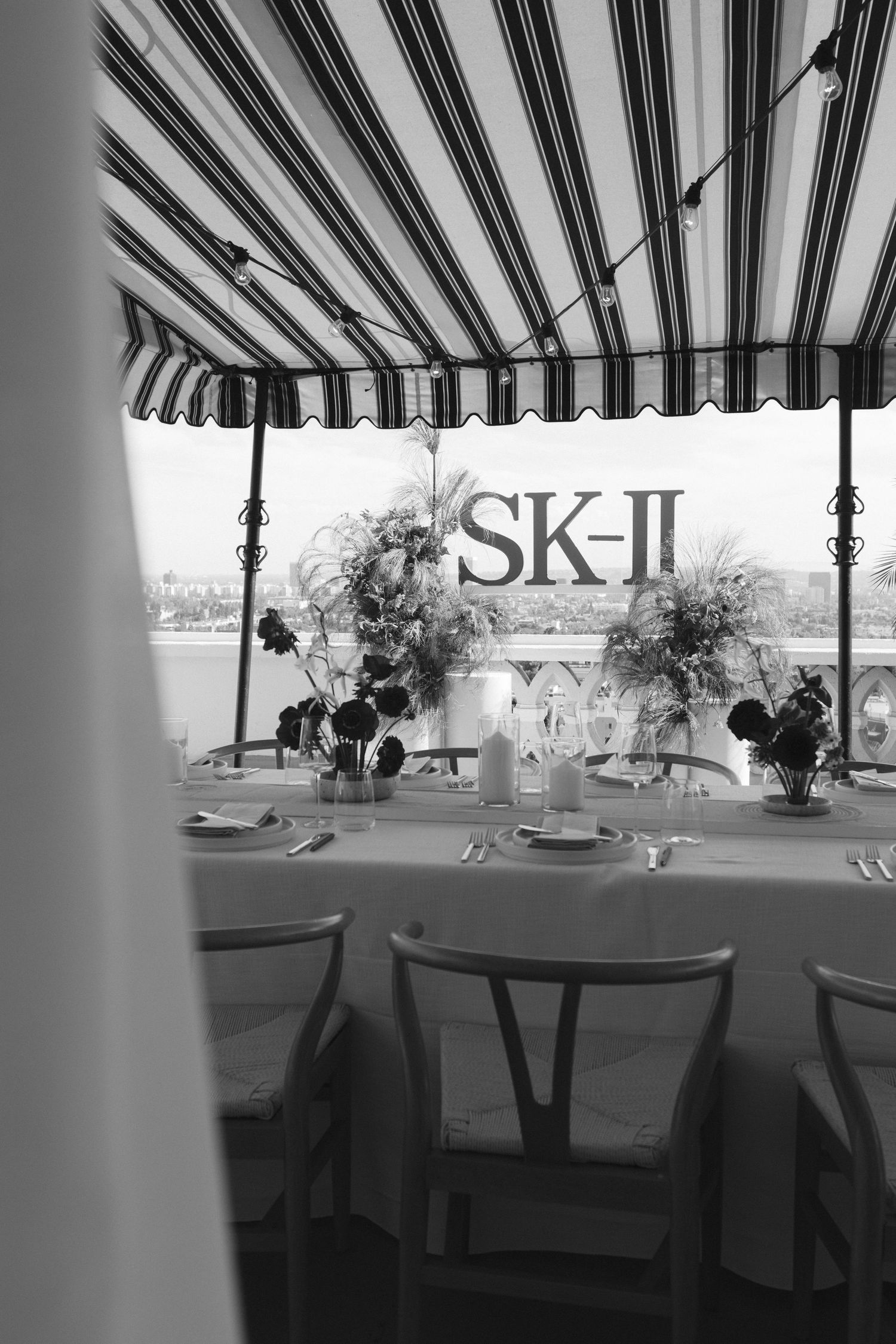 Black and white dining setup under striped awning with SK-II branding visible.