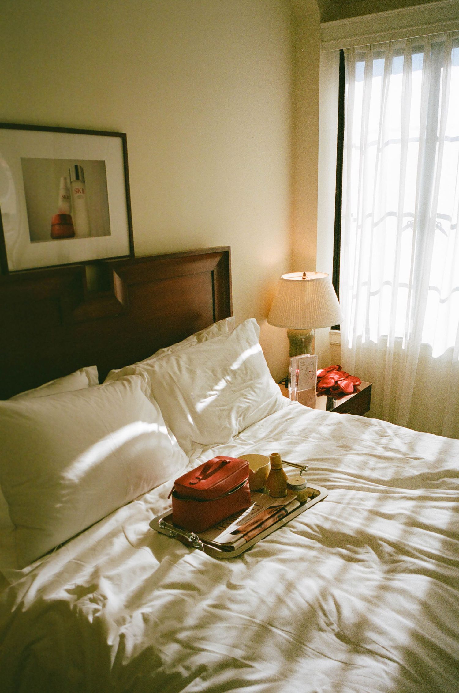 Unmade white hotel bed with rumpled sheets and natural lighting from window.