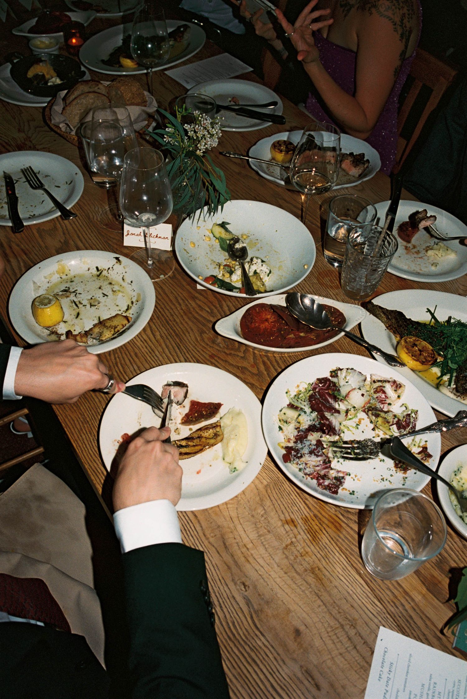 Overhead view of dinner plates and wine glasses on wooden table at restaurant.