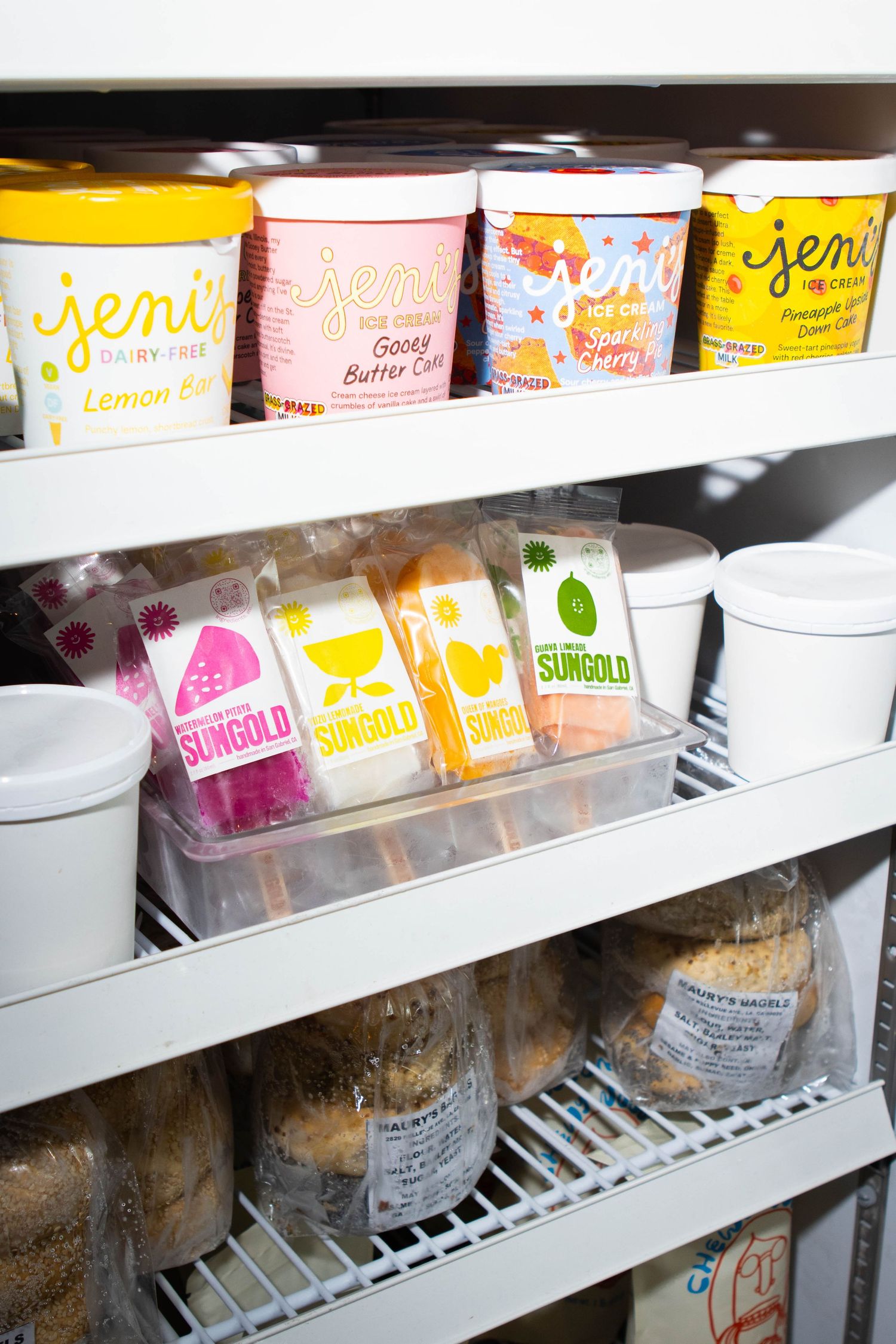 Colorful ice cream containers and frozen treats displayed on refrigerated shelves.