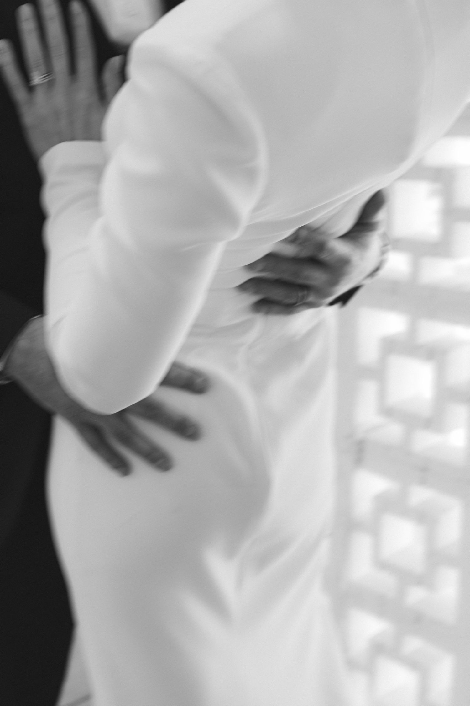 Abstract close-up details of a white wedding dress against a patterned wall.