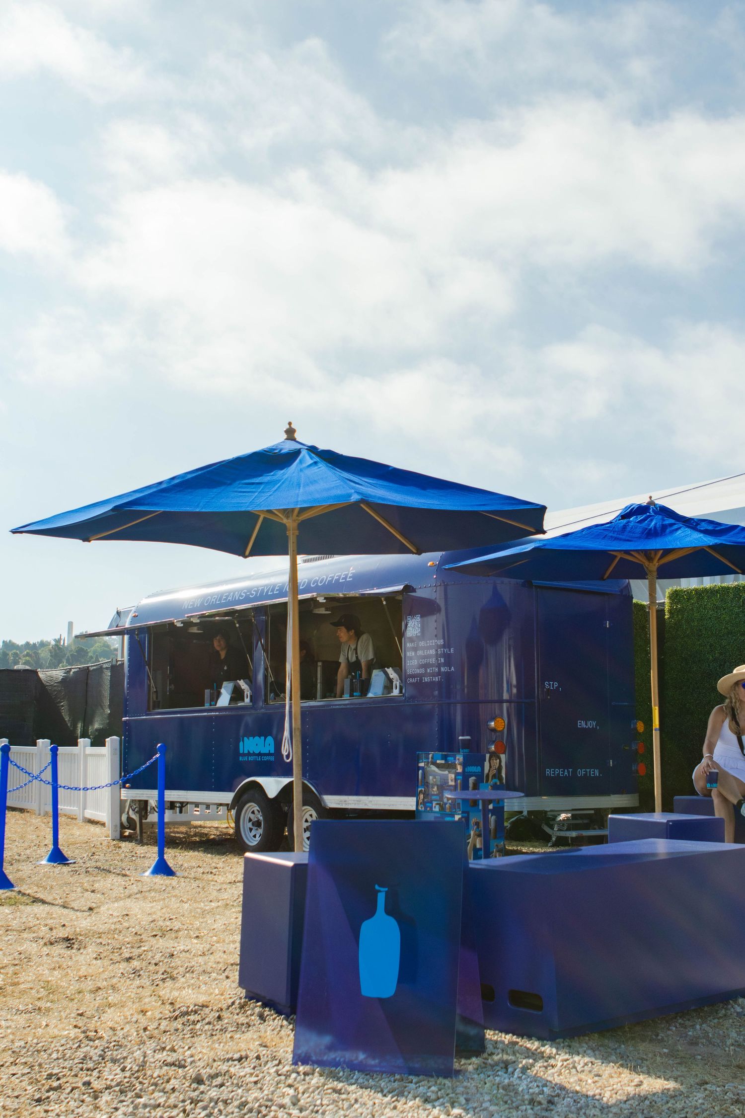 Blue outdoor coffee kiosks with umbrellas set up at an outdoor event.
