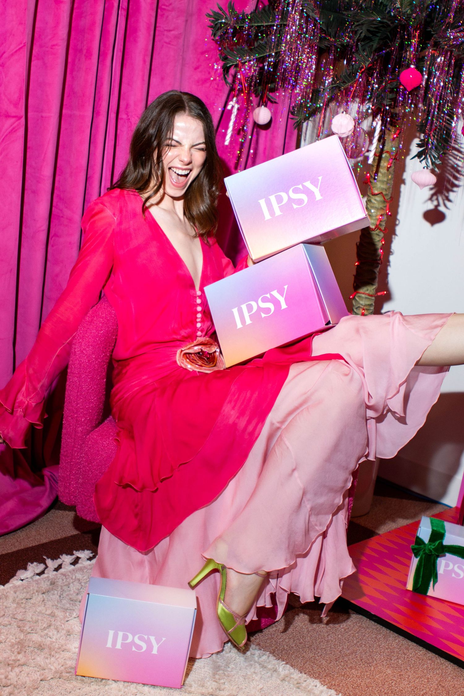Woman in bright pink outfit surrounded by gift boxes and party decorations.