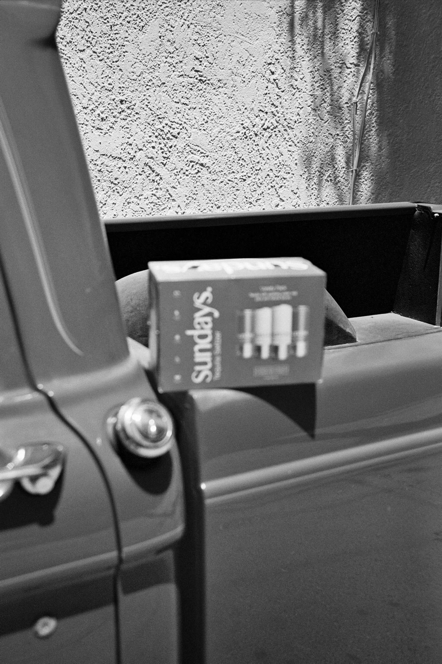 Black and white image of a car door handle and window frame.
