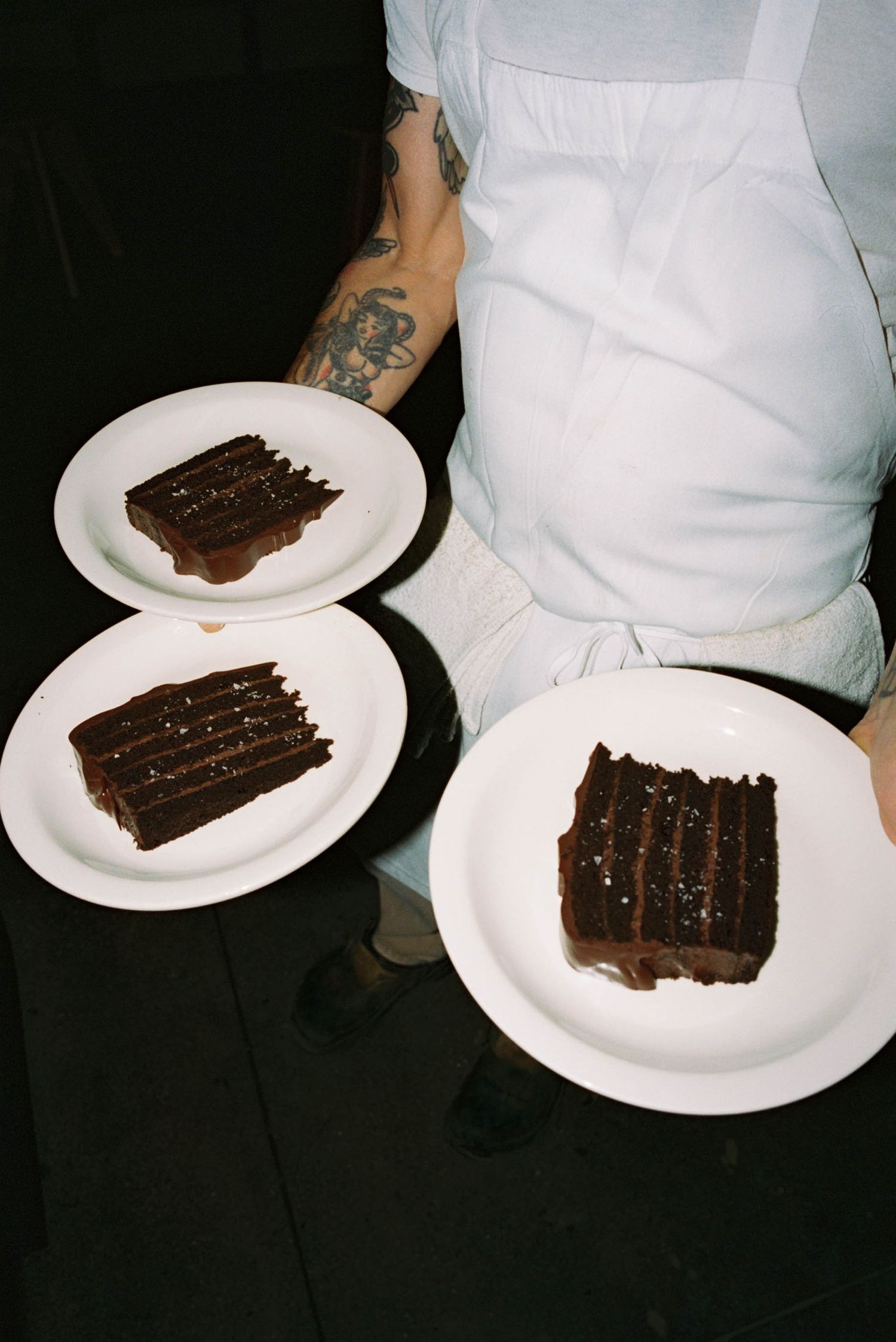 Multiple slices of chocolate cake served on white plates.