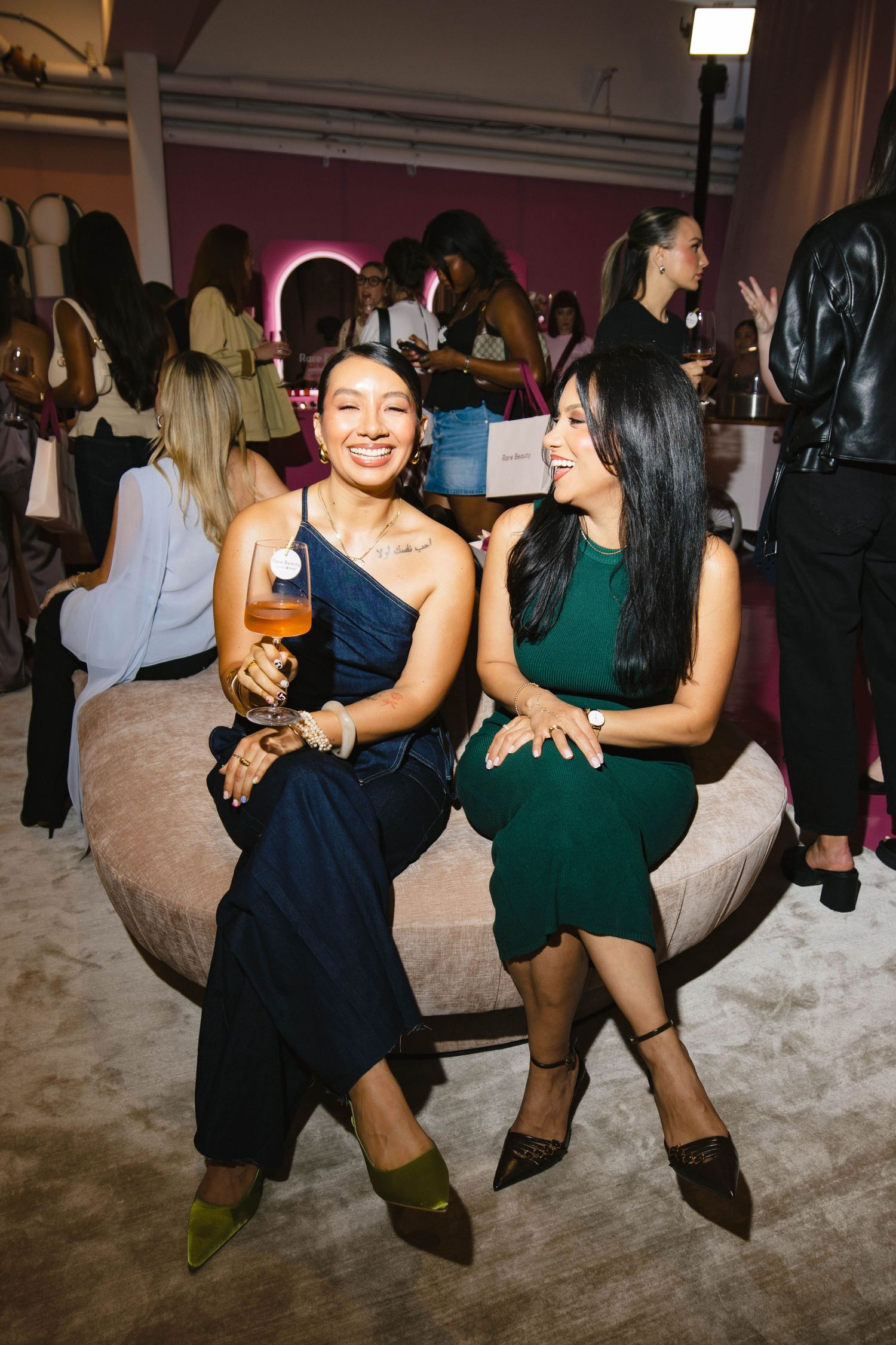 People dancing together at a party on a dance floor in black and green dresses.