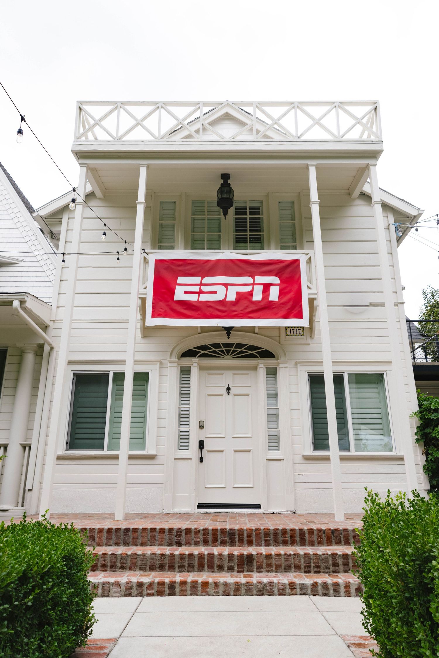 White colonial style house with ESPN banner displayed on the front.