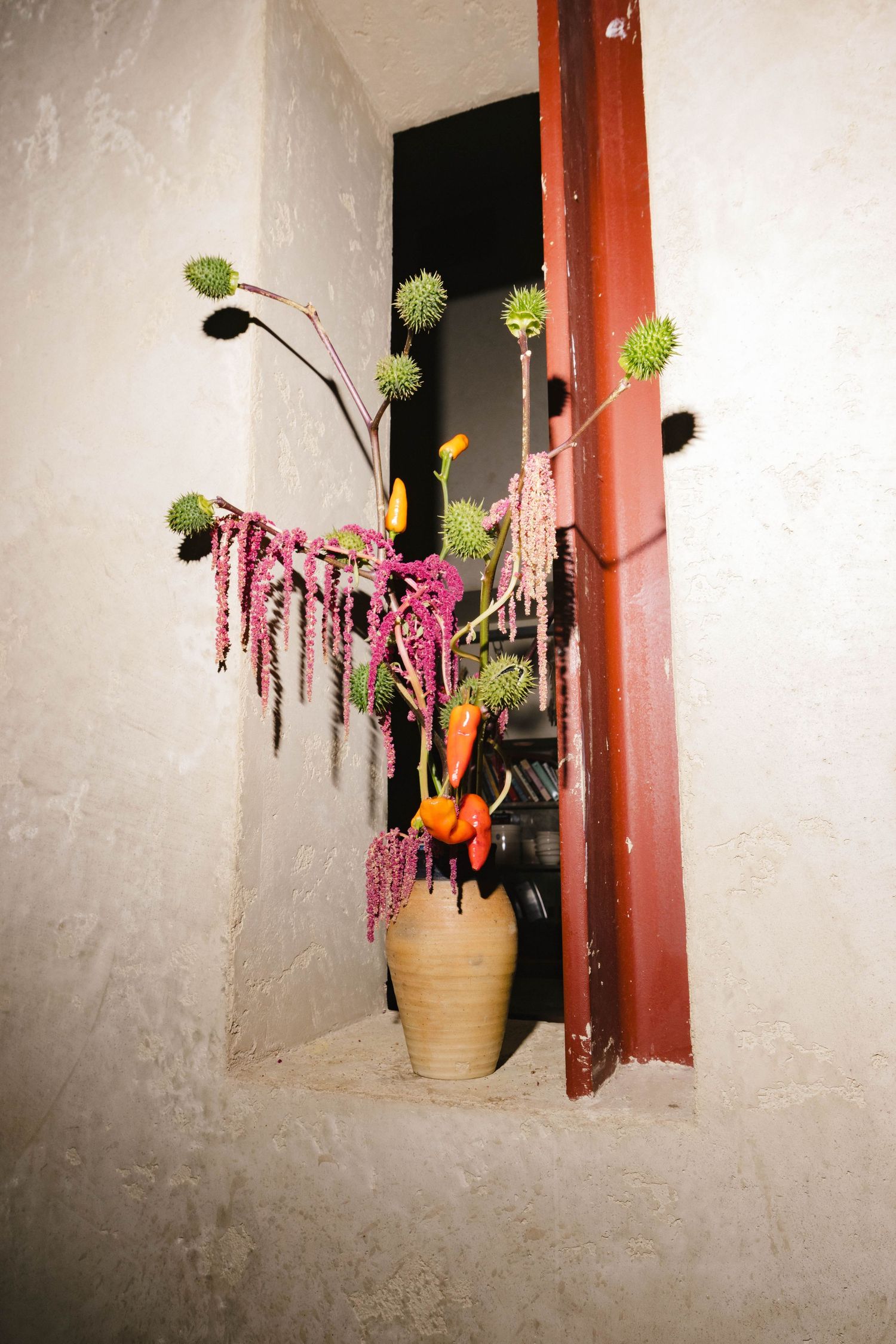 Colorful floral arrangement with pink blooms displayed in a rustic window frame.