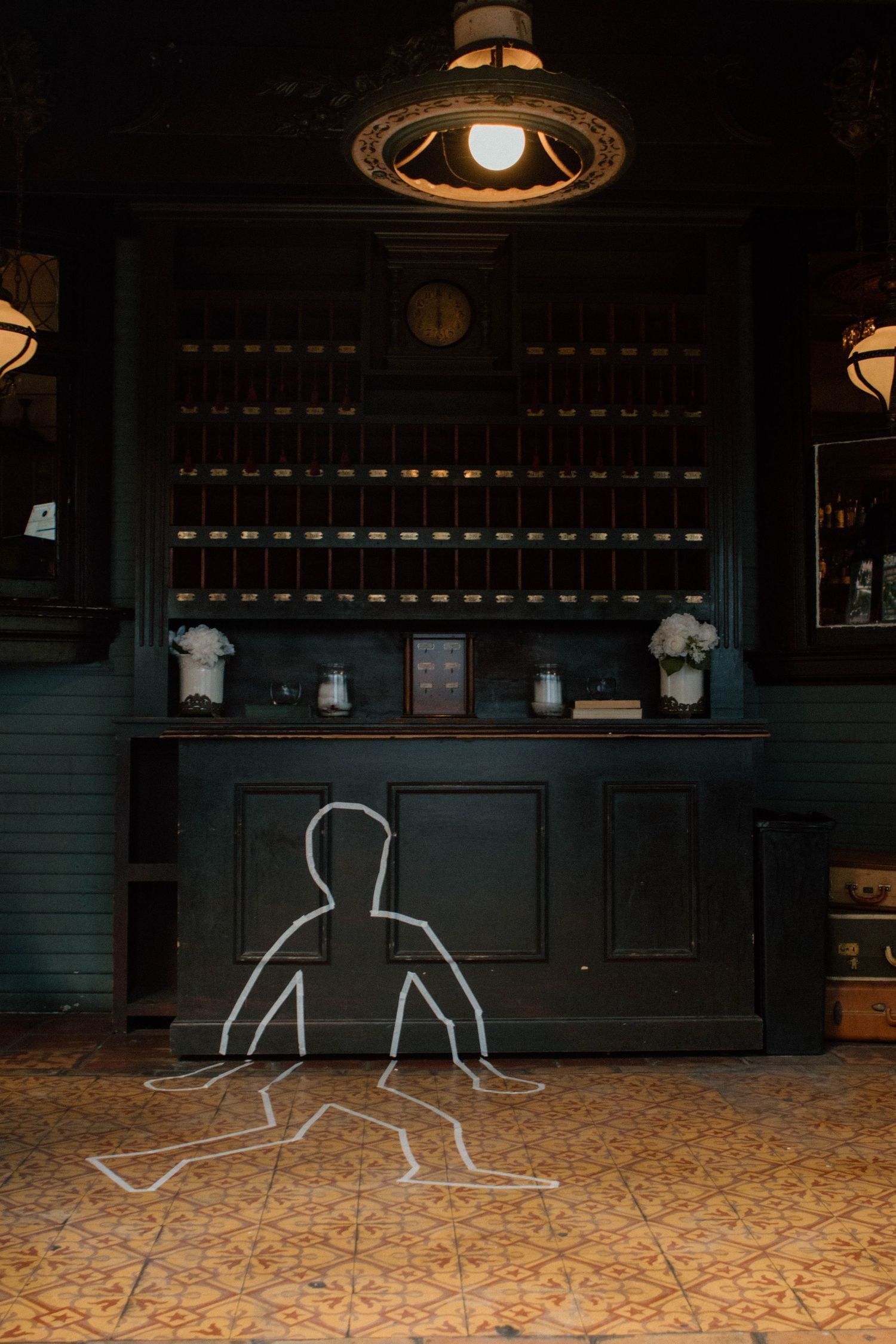 Chalk outlines of figures drawn on a dark floor under dim lighting.