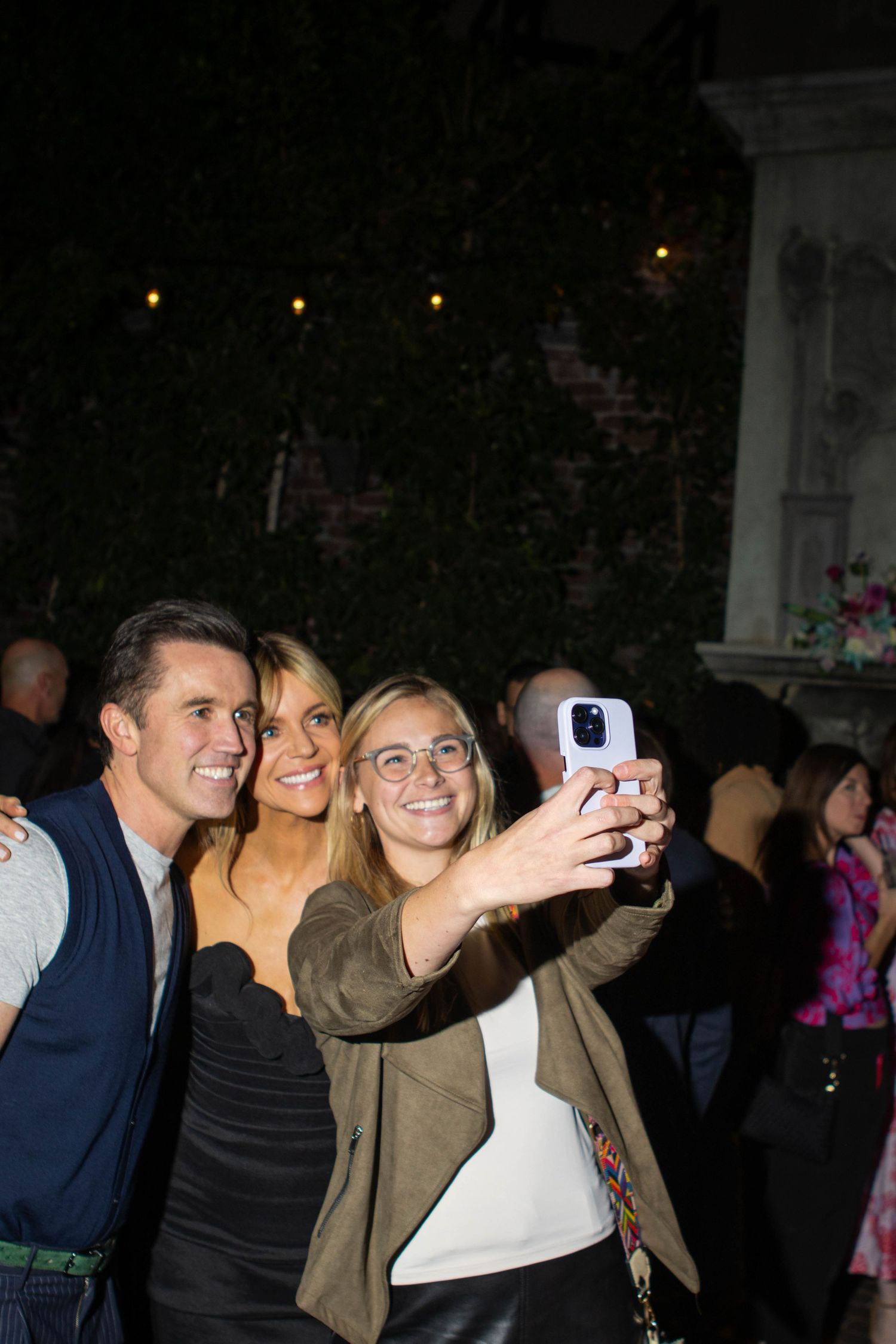 Group of people taking selfies together at a nighttime event.