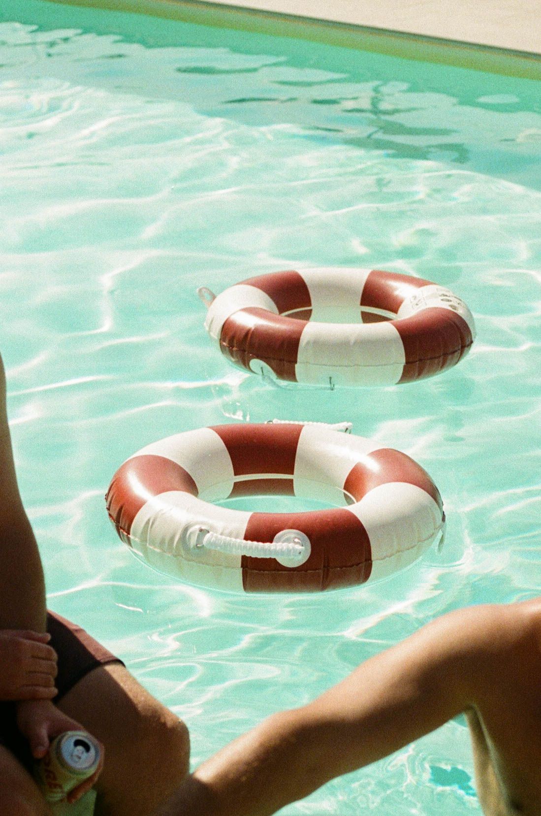 A red and white life preserver ring floats in turquoise pool water.