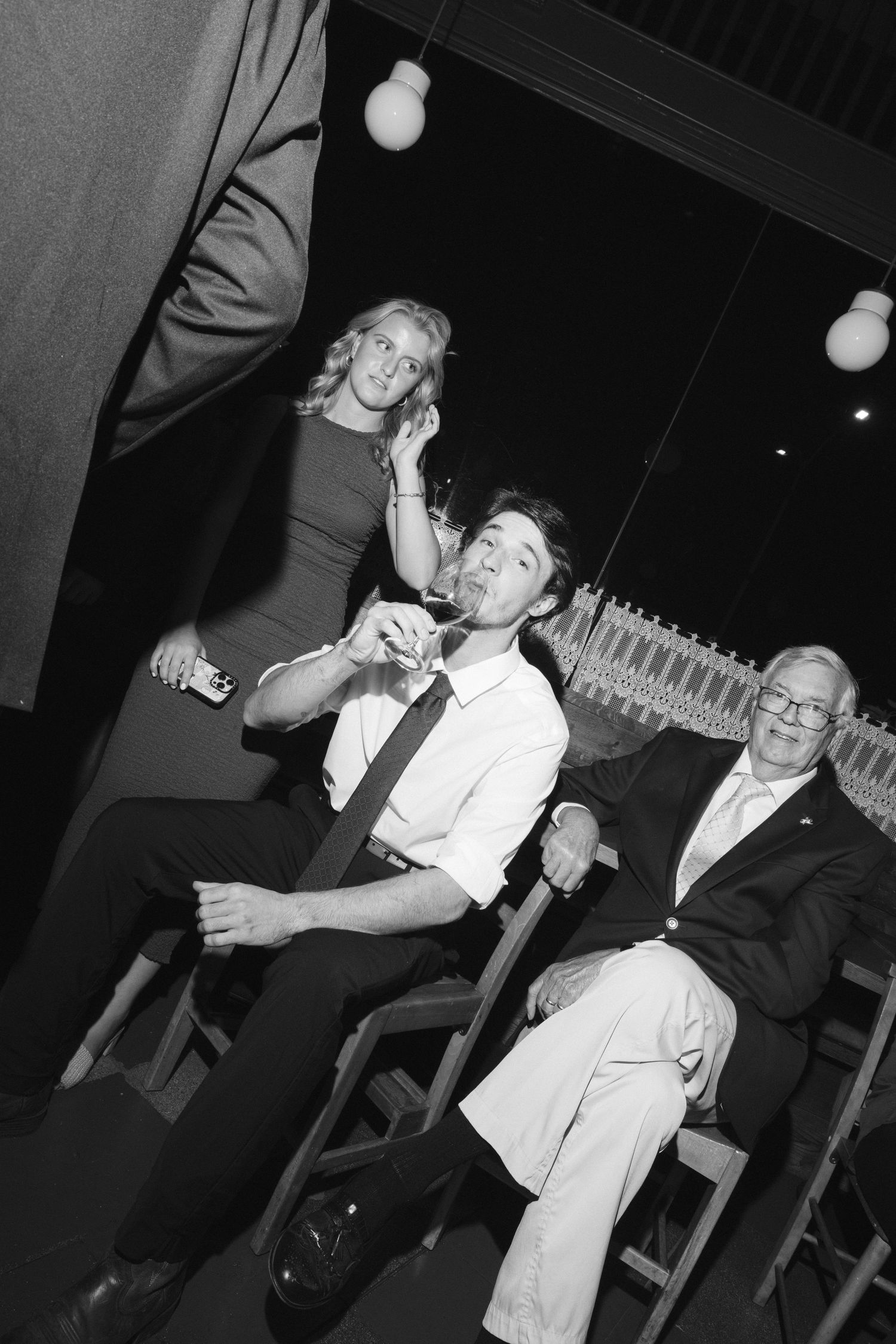 A sequence of black and white photos shows people in formal attire sharing laughter and animated conversation at an event.