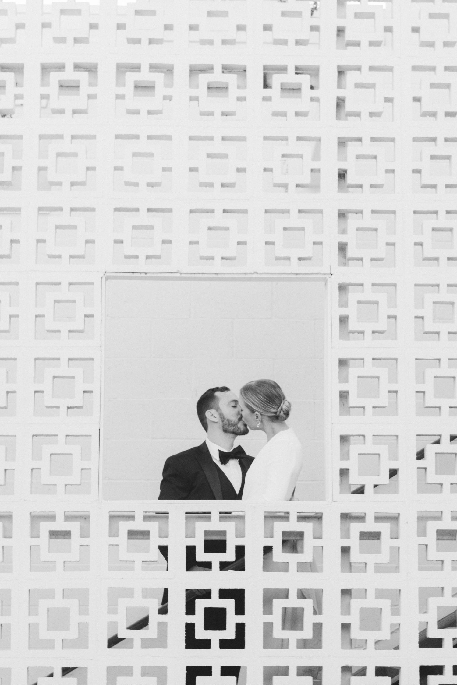 Romantic black and white portrait through geometric pattern wall detail.
