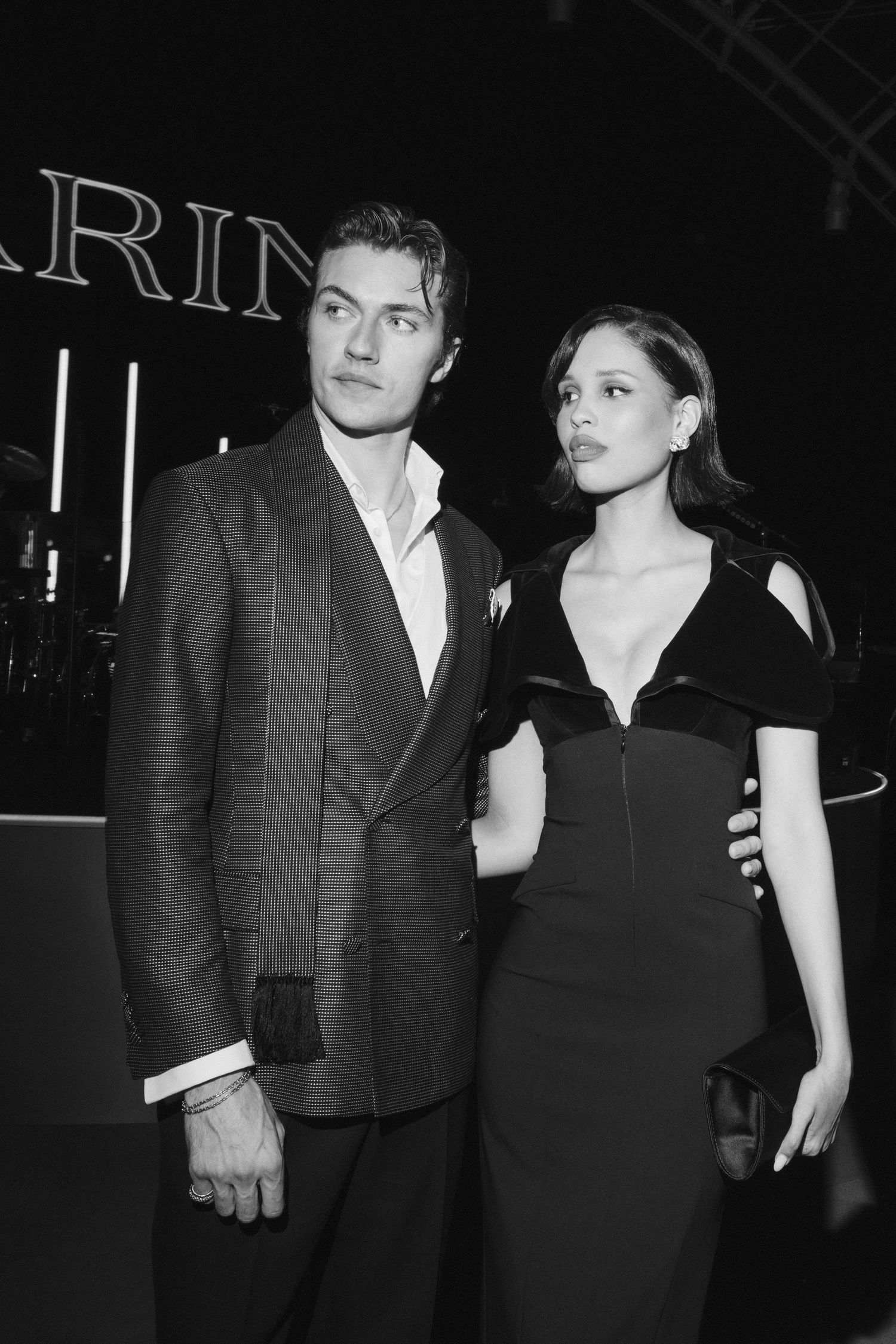 Black and white photo of an elegant couple posing at a formal event, man in suit, woman in black gown.