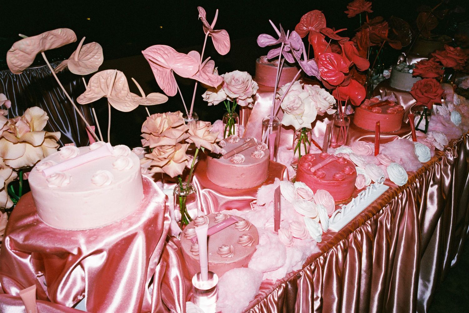 Pink satin tablecloth adorned with delicate floral arrangements and decorative elements at a formal event.