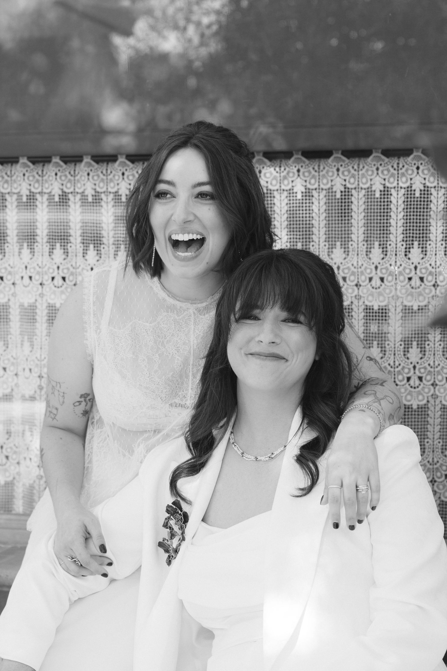 A series of black and white portraits showing joyful expressions against a lace curtain backdrop.