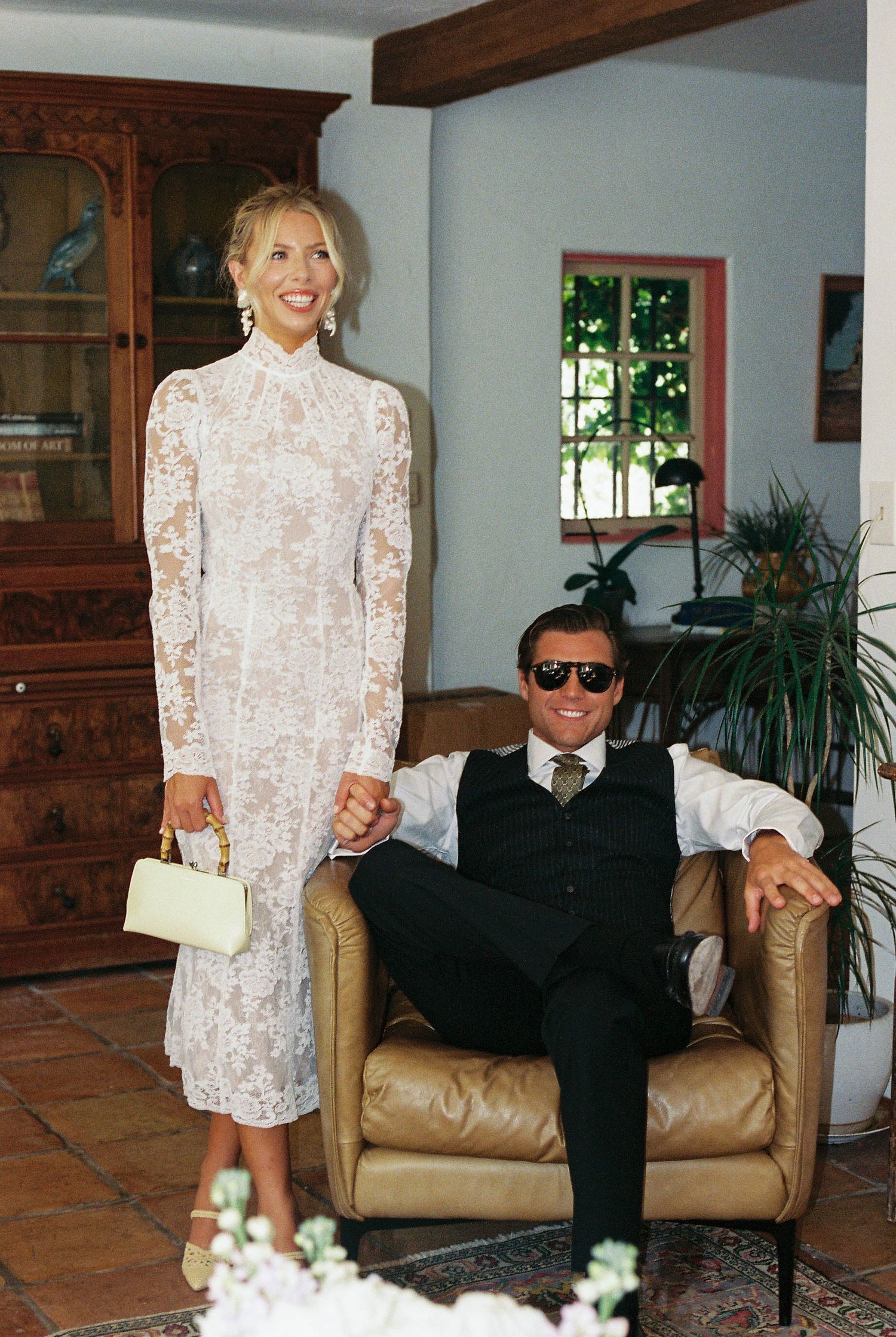Interior scene showing a leather couch with black and white formal attire in a room with wooden beams and plants.