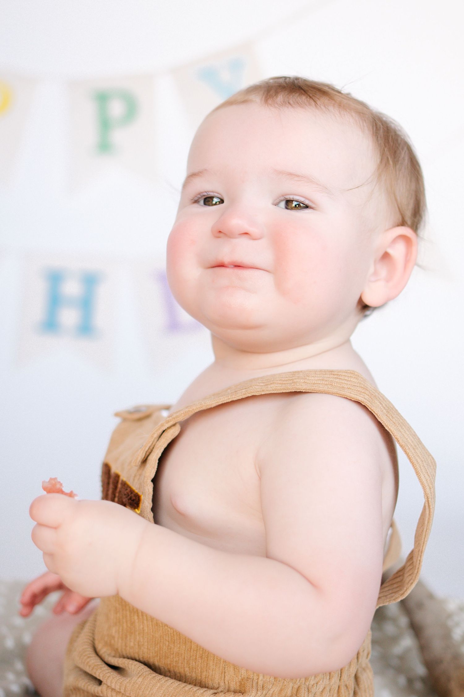 Toddler boy in overalls during a 1st birthday milestone session. Professional photography in Warner Robins, GA by C + F Photography.