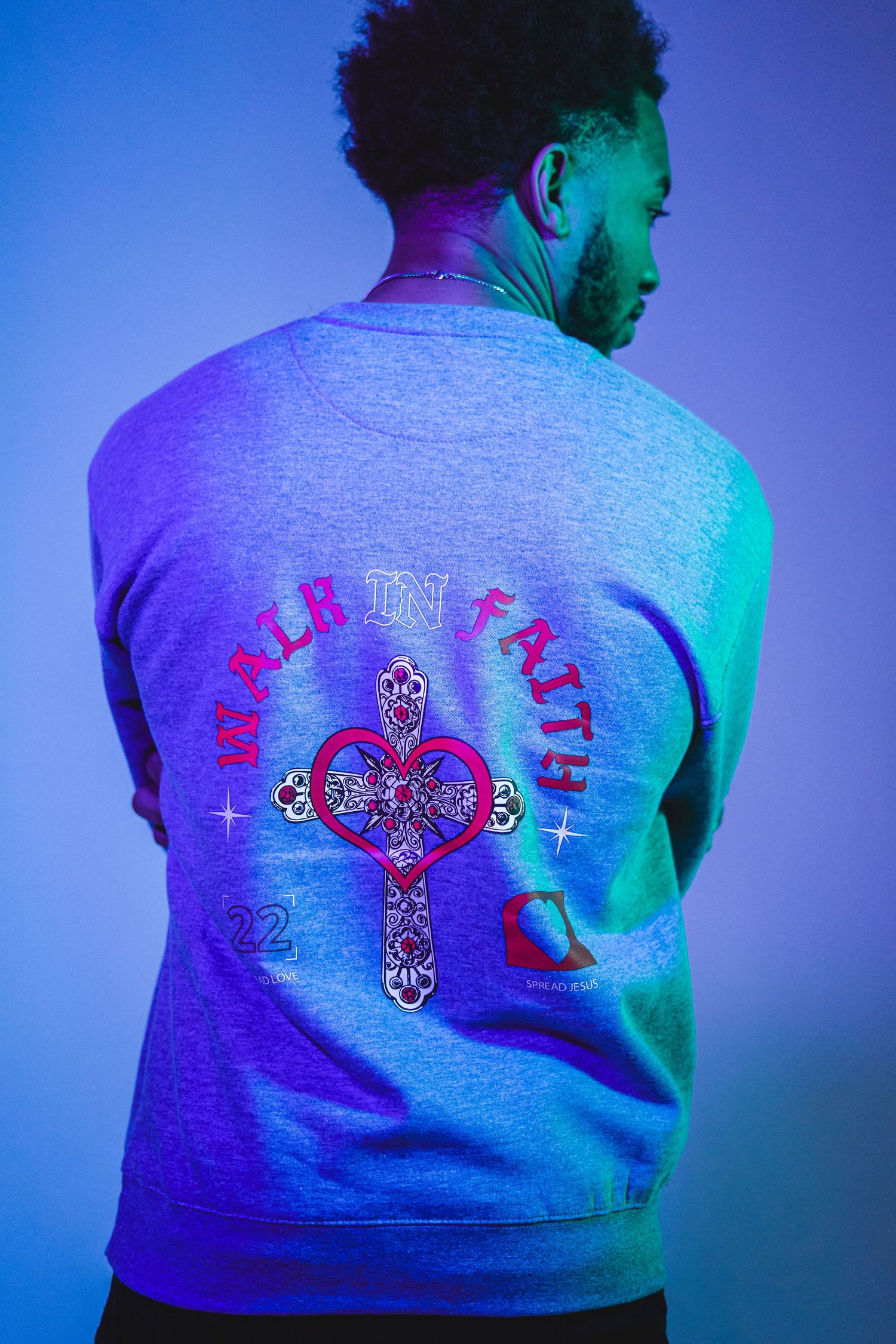 Gray sweatshirt with colorful graphic design shown under purple and blue lighting.