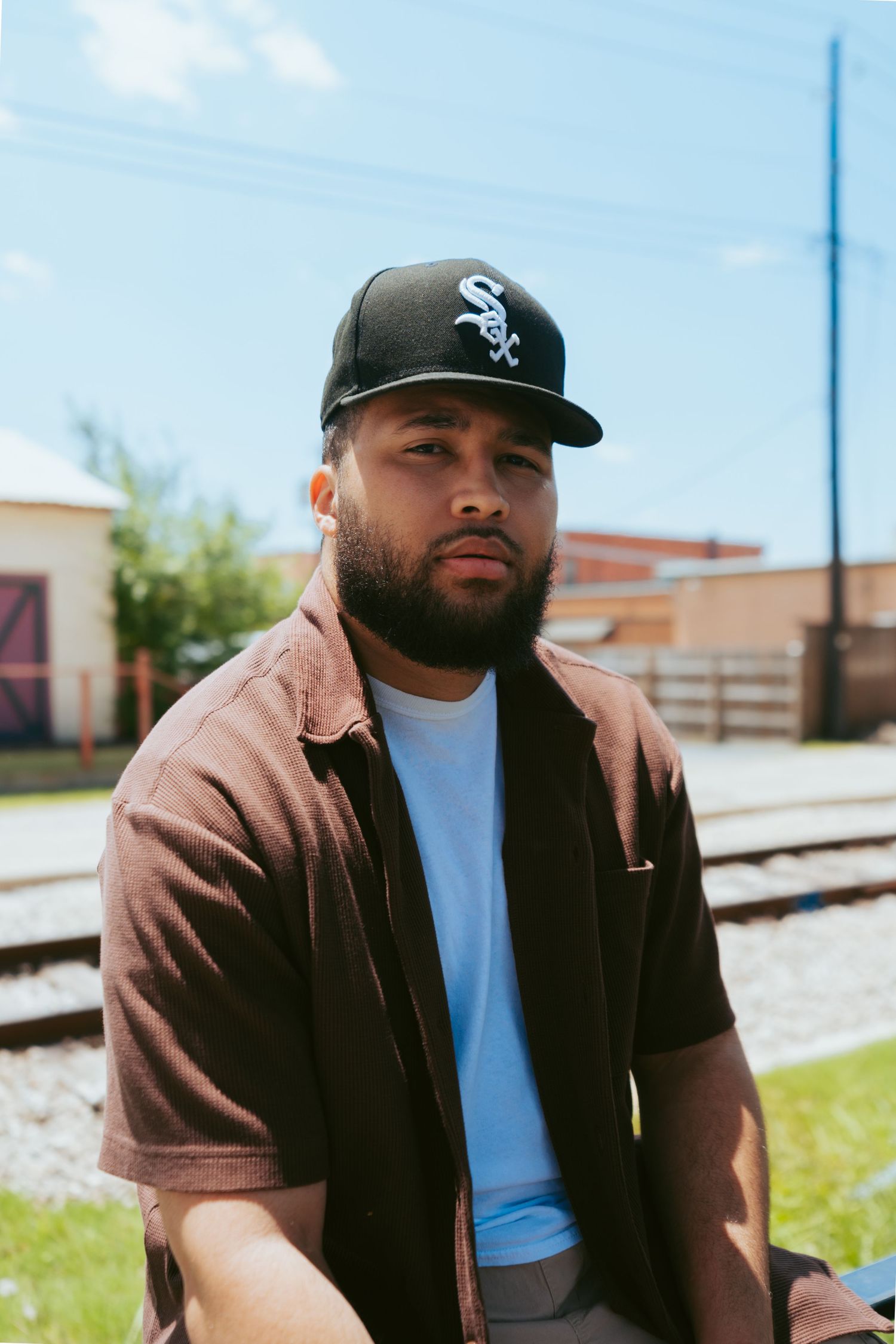 Man in casual attire sitting outdoors wearing a White Sox baseball cap.