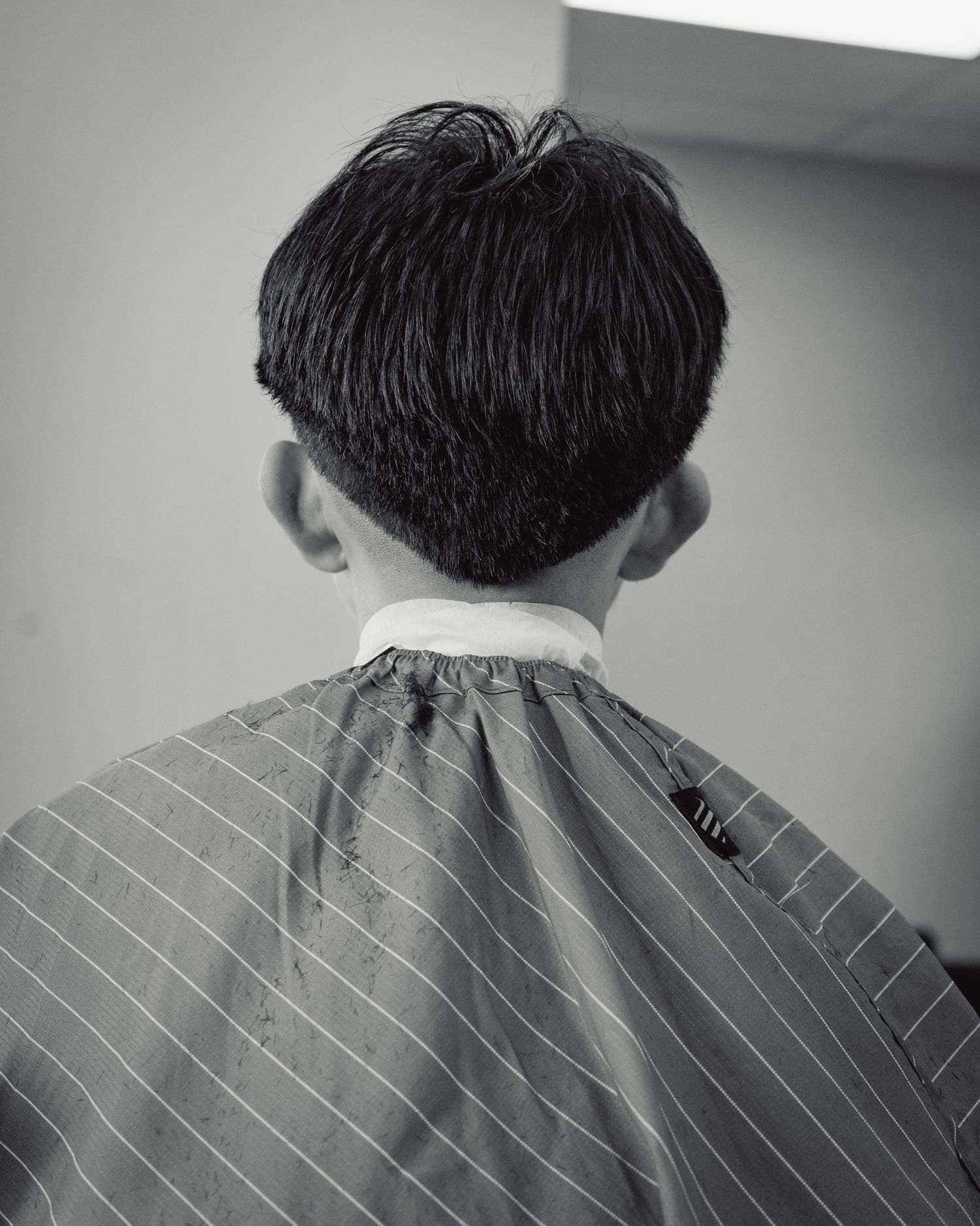 Black and white photo series showing back of head with short dark hair and striped collar.