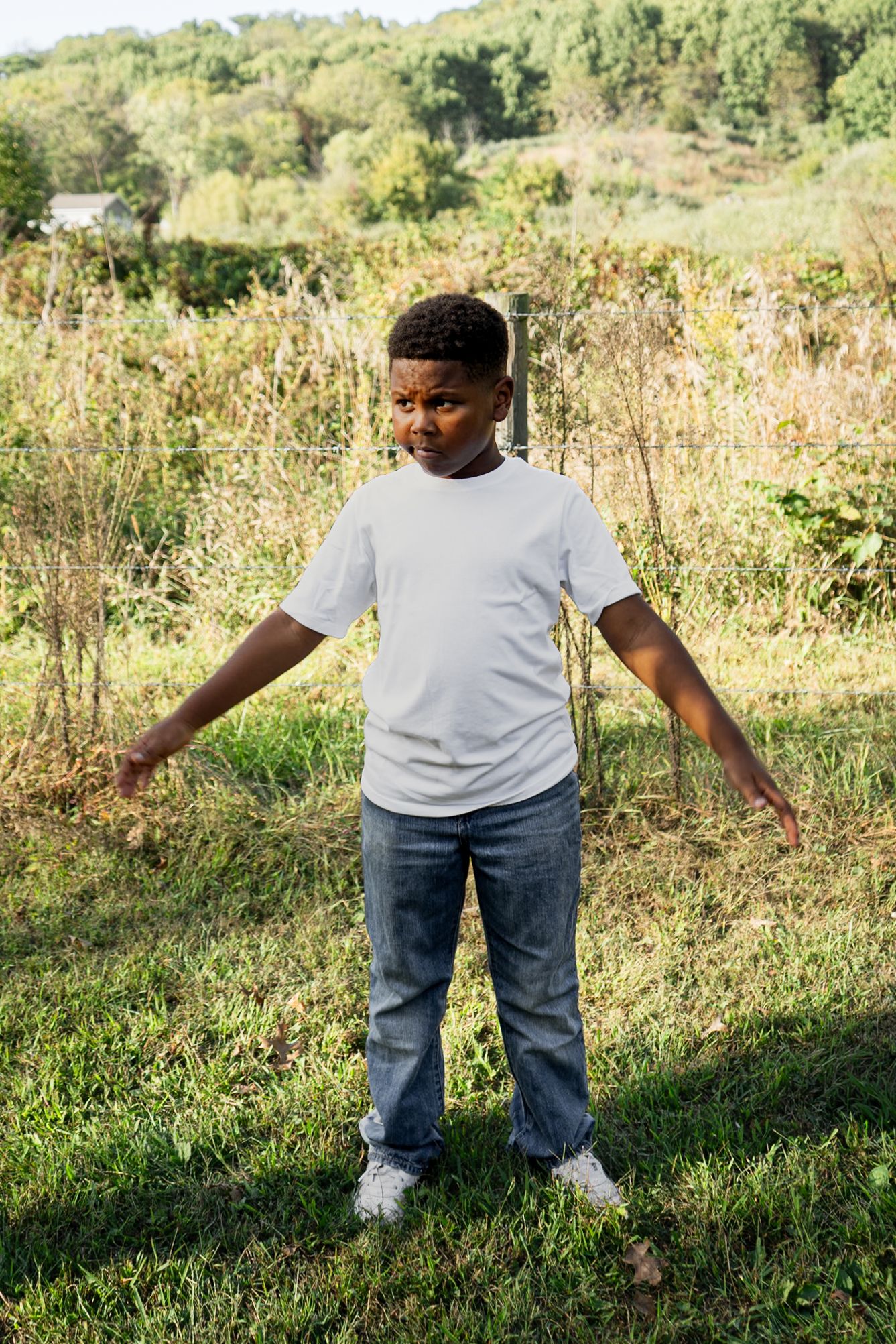 Playful outdoor photos showing movement and dancing poses on grass with trees in the background.
