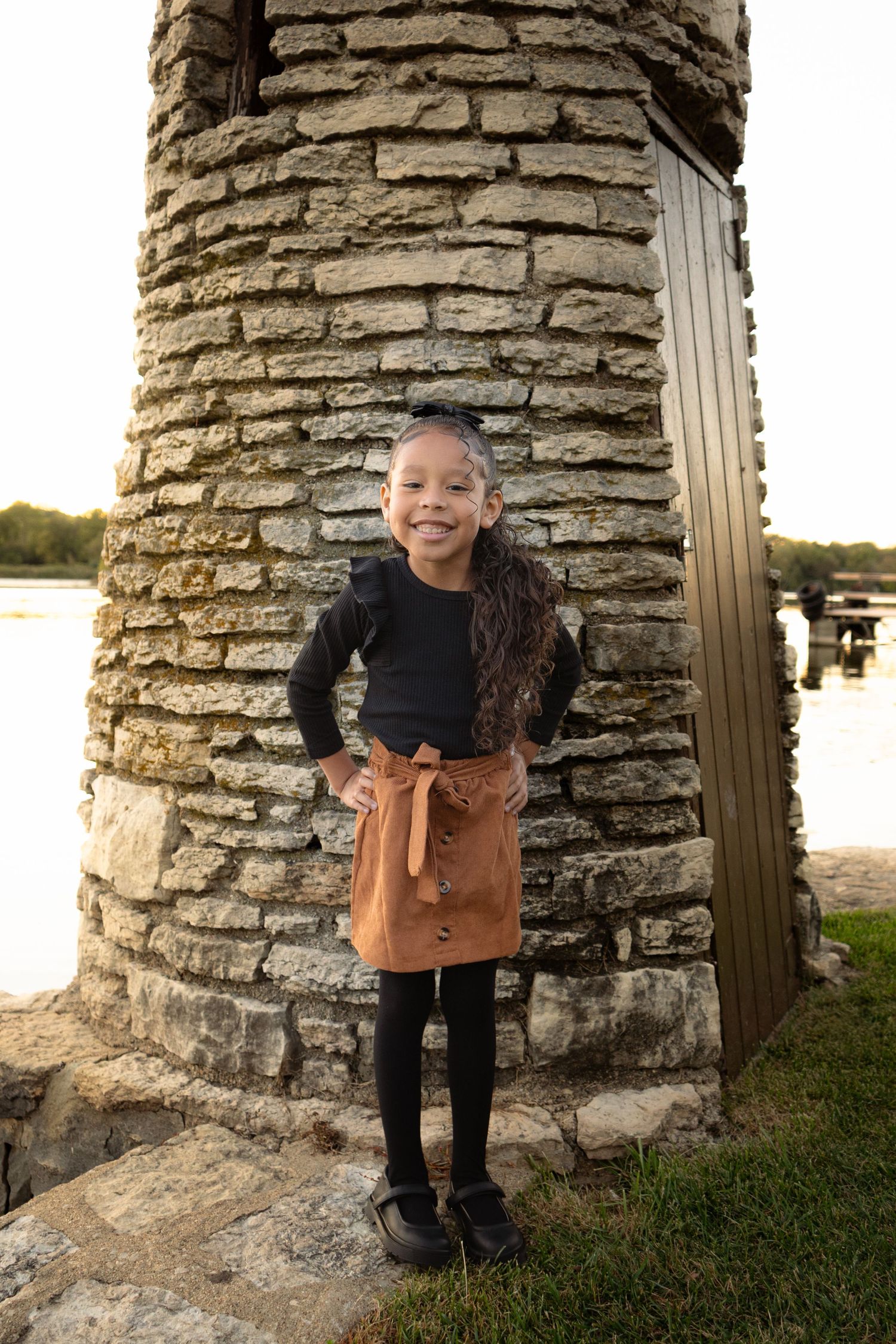 Playful portraits taken between stone columns with a lake view at golden hour.