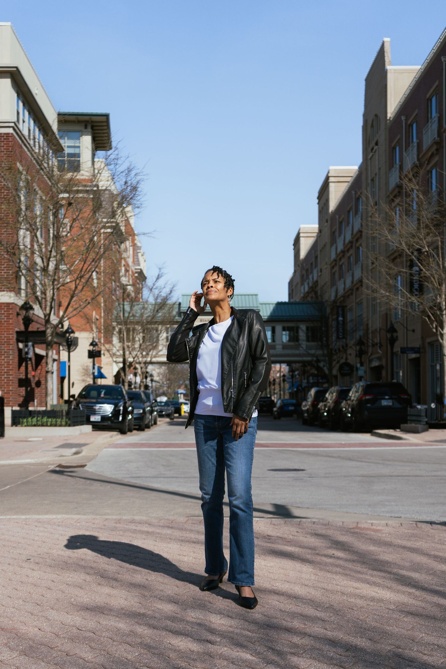 Four sequential photos show someone standing in a brick courtyard between modern buildings on a sunny day.