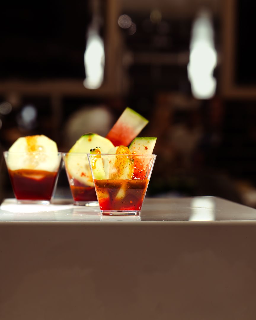 Colorful cocktails with garnishes arranged on an illuminated bar counter.