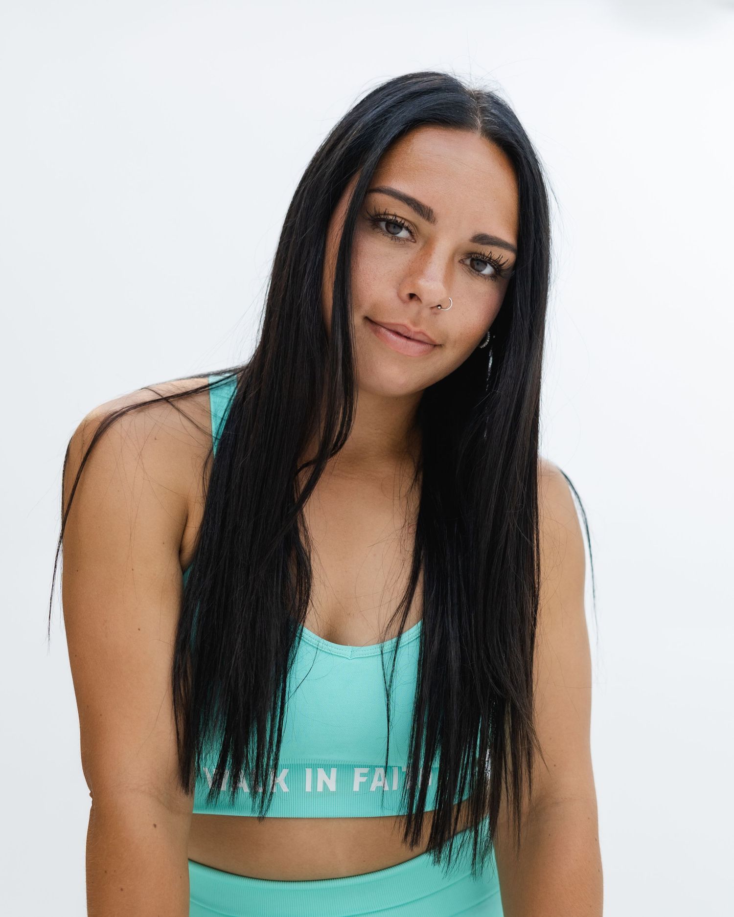 Woman with long dark hair wearing a turquoise athletic top poses in three different positions against white background.