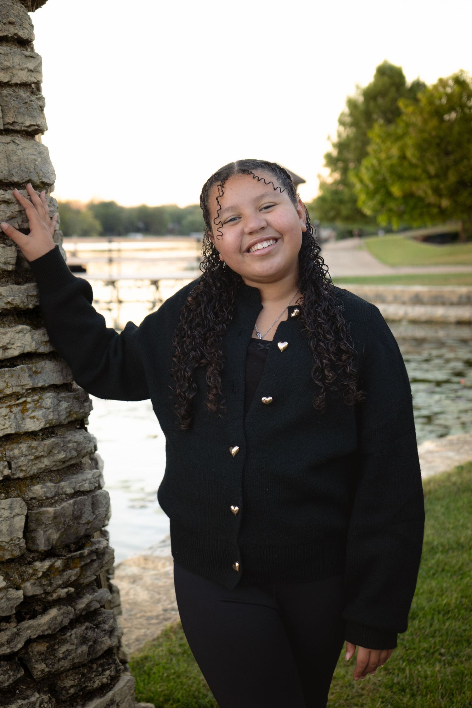 Expressive poses captured against stone pillars near a waterfront at sunset.