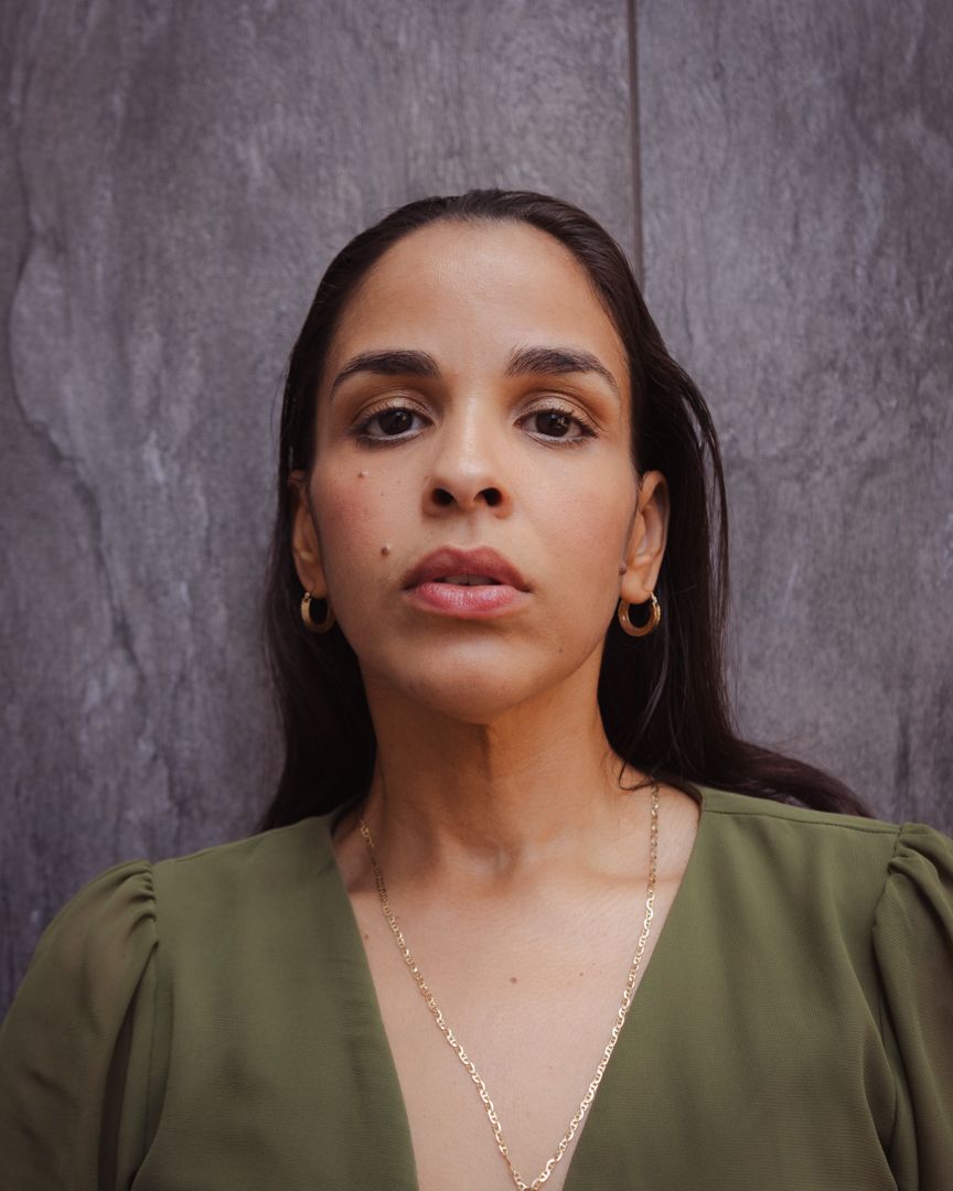A woman in an olive green top poses against a gray backdrop in a series of expressive headshots.
