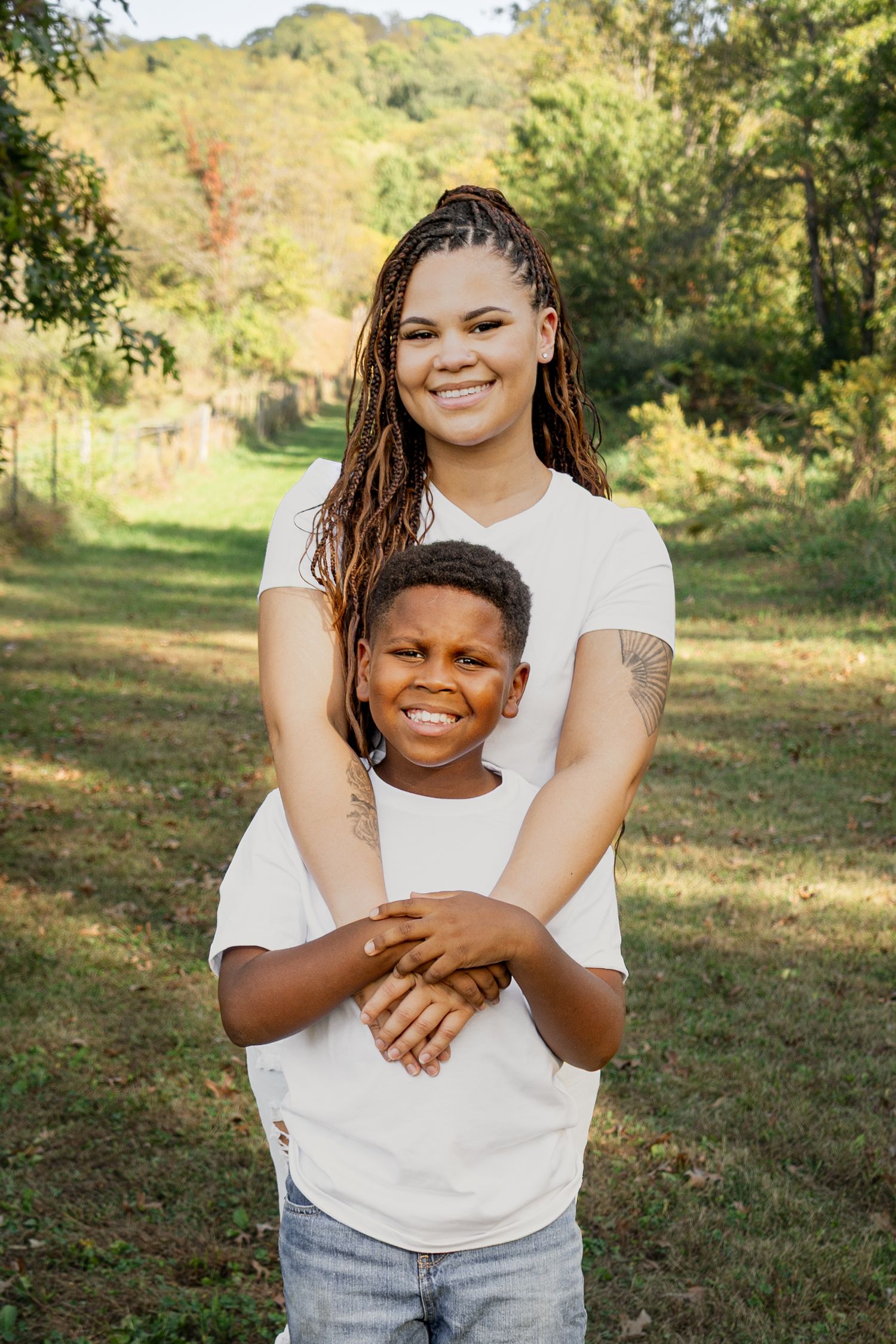 Candid outdoor photos showing warm embraces and genuine laughter in a sunlit natural setting.