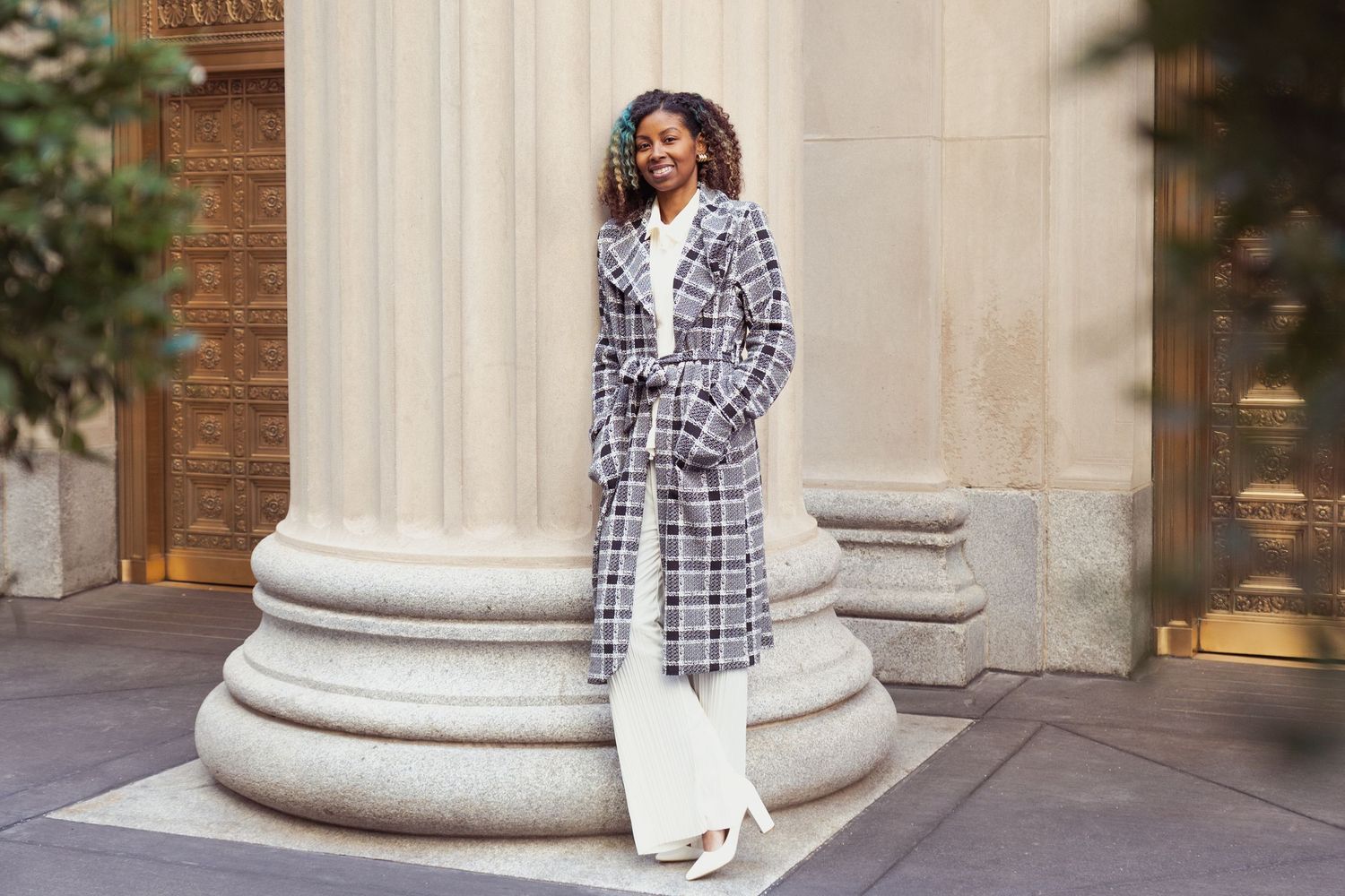Editorial fashion shoot against classic architecture with white columns and brick walls.