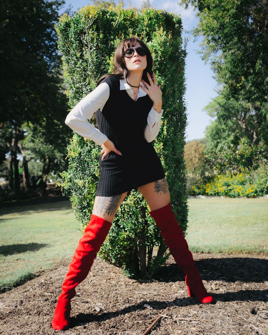 Stylish figure in red boots striking dramatic poses against garden backdrop.