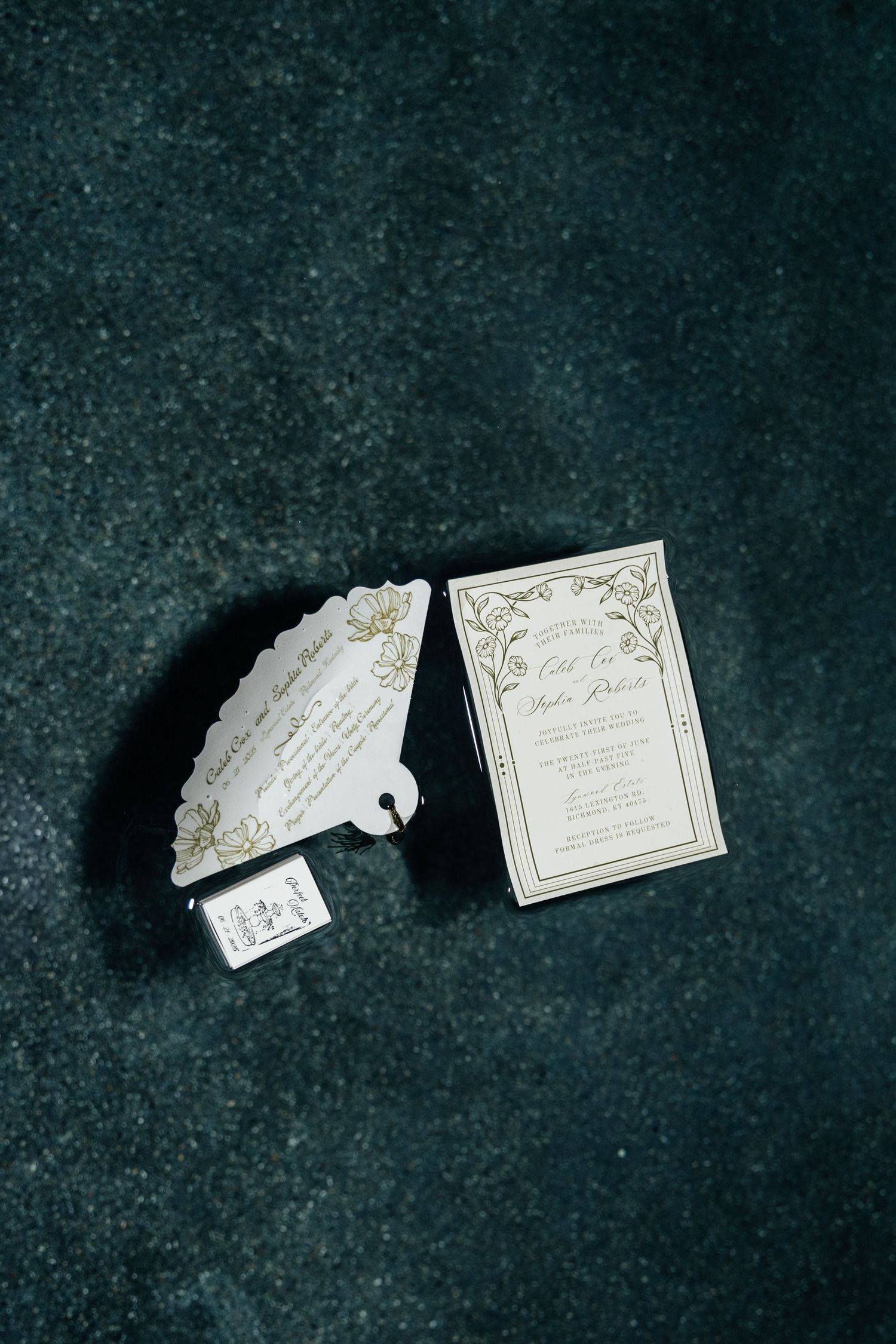Elegant white and gold wedding invitations with ornate details in water fountain.
