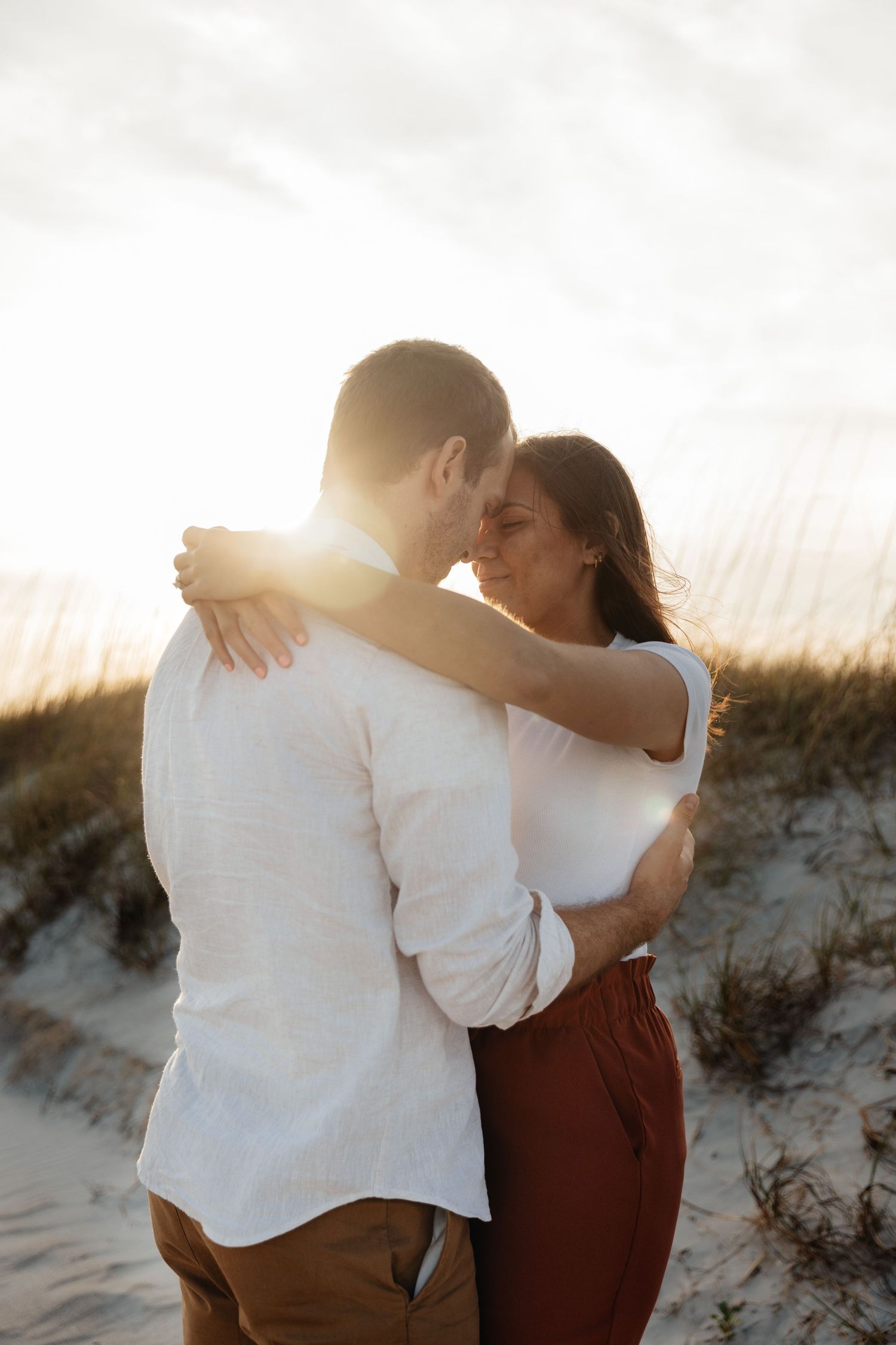 Romantic couple embracing on sandy beach during golden hour.