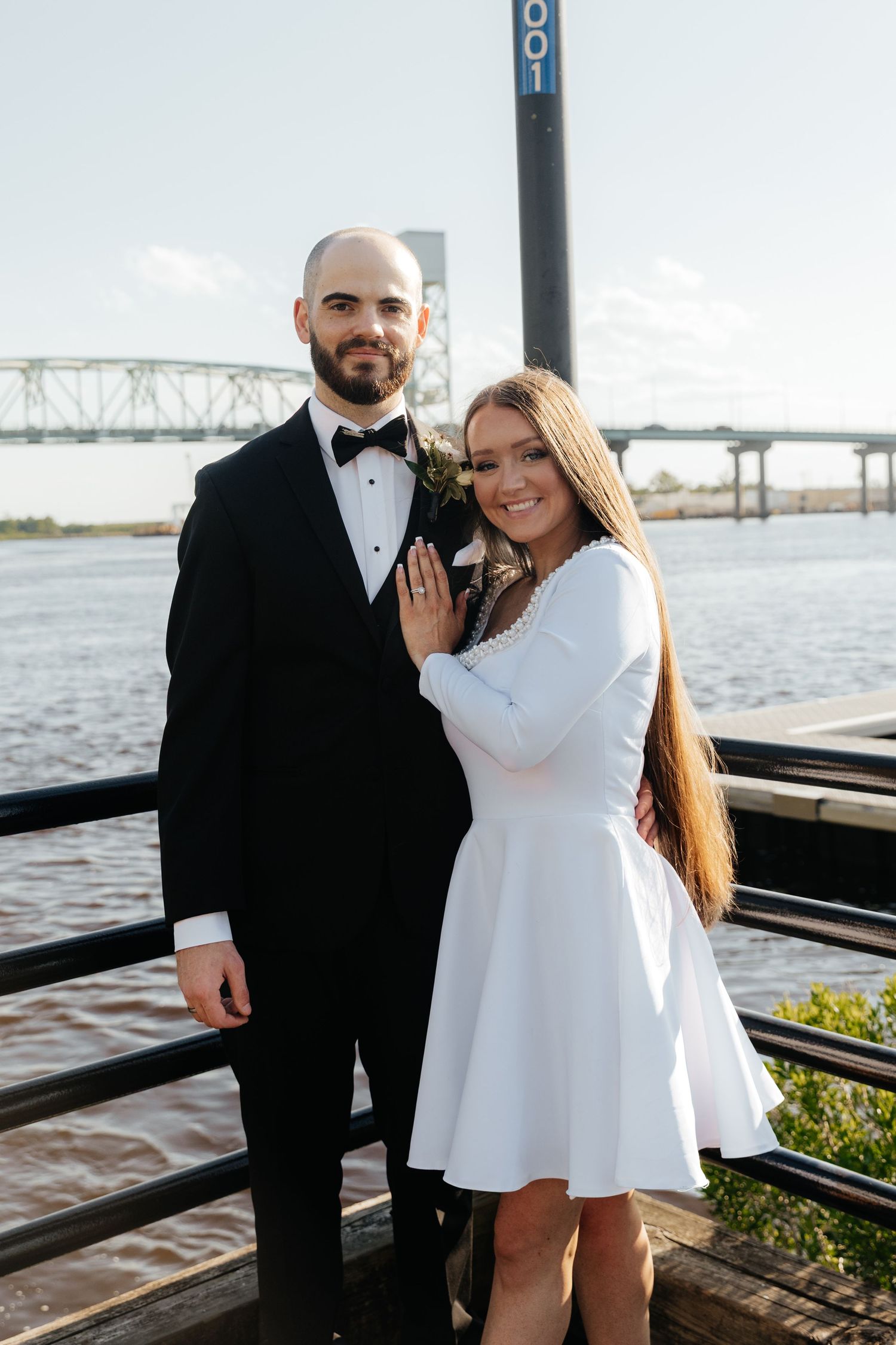 A happy couple shares a romantic moment on a riverside deck after their wedding ceremony.
