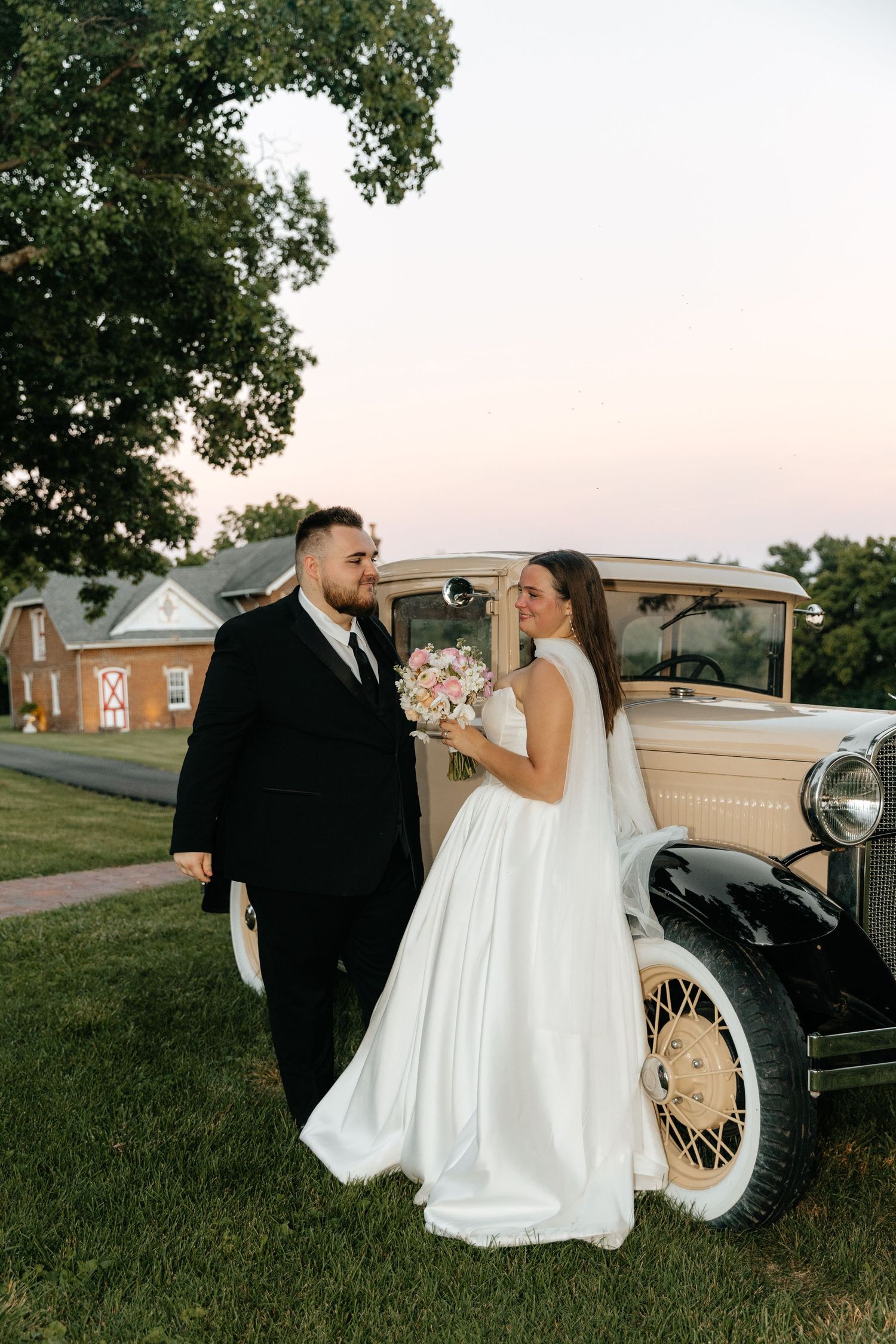 Romantic wedding photos with vintage car in golden evening light.