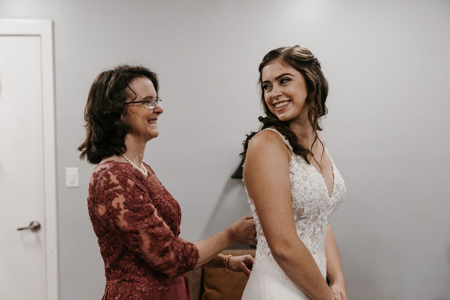 Final moments of wedding dress preparation with mother of the bride.