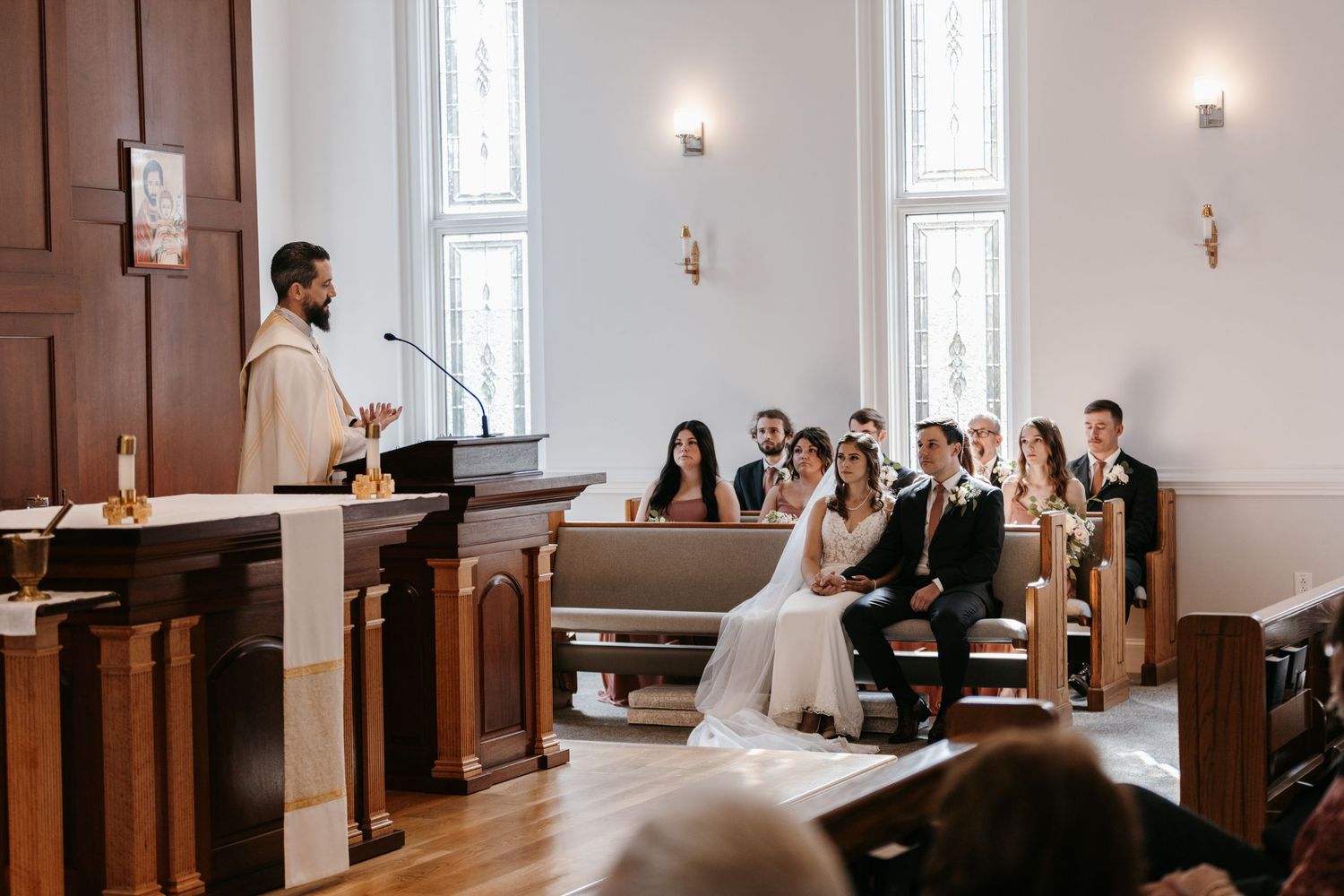 Wedding ceremony in progress in a bright church sanctuary with wooden pews.