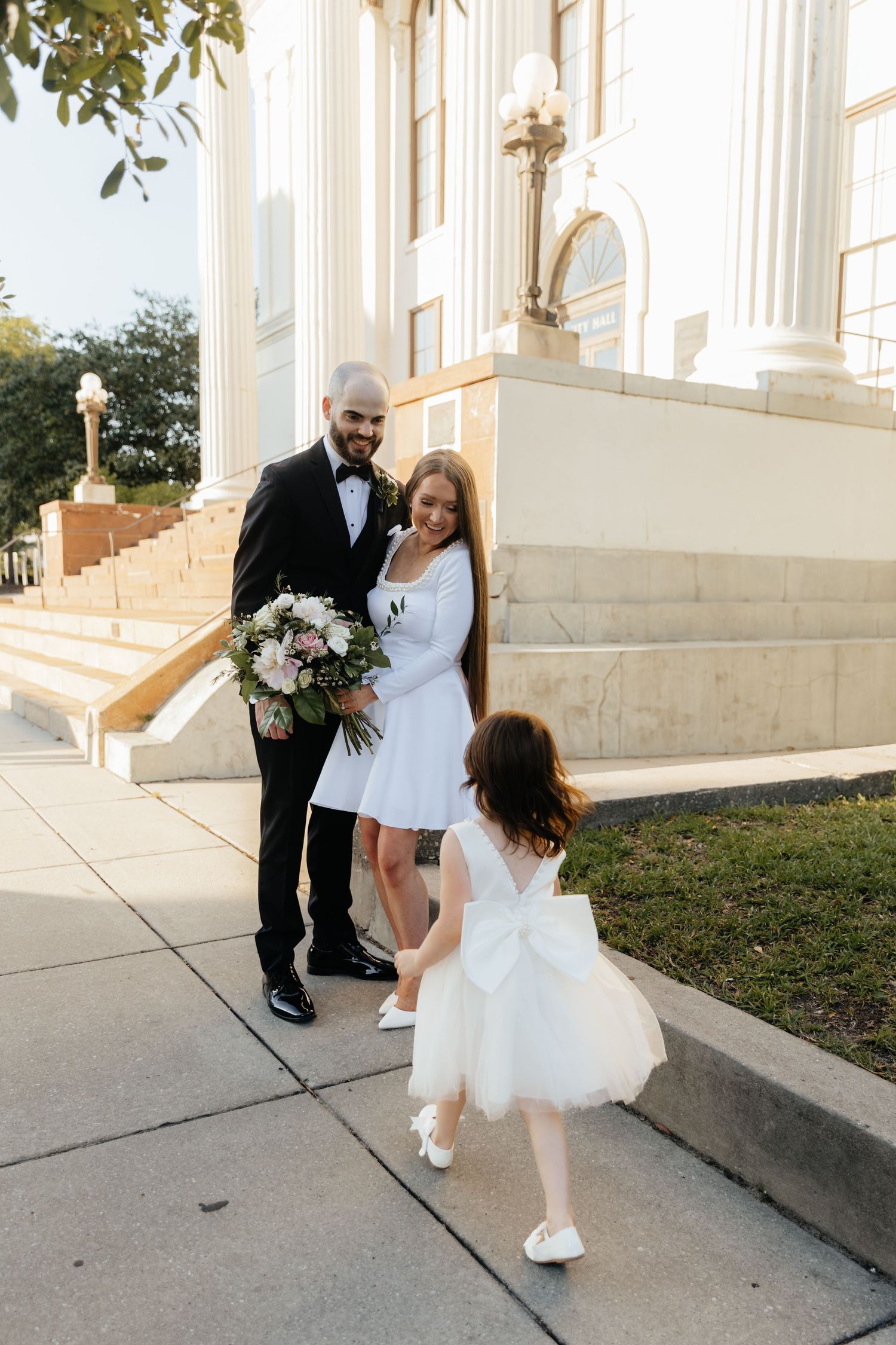 Playful wedding photo sequence on the steps of a historic building with white columns.