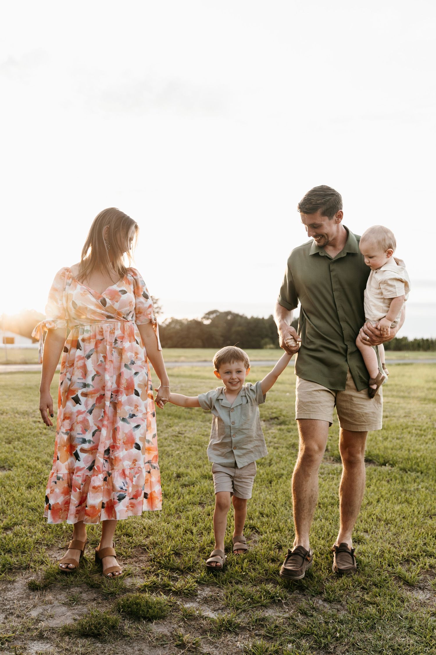 Family walking together through a sunlit field during golden hour.