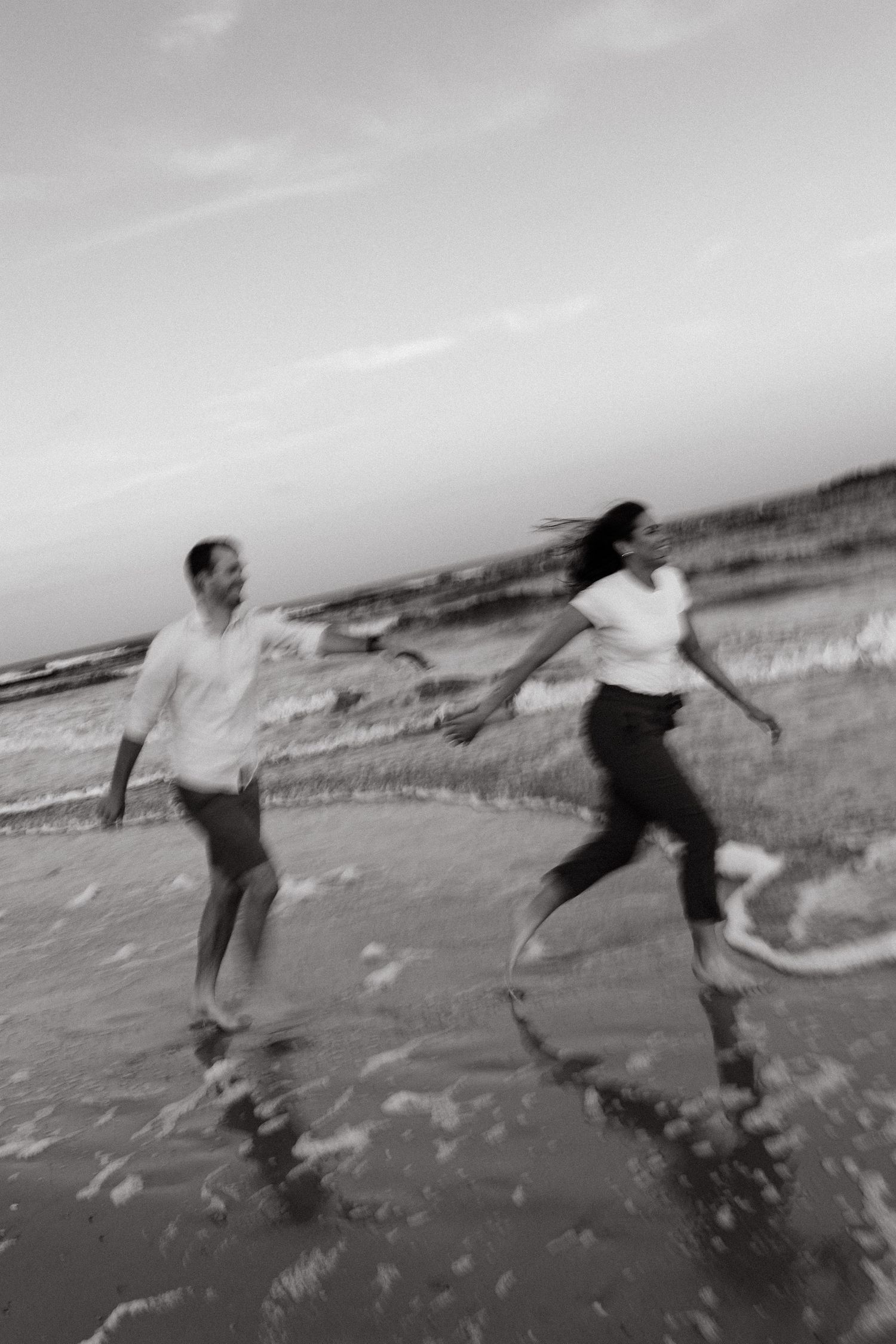 Motion-blur photos of a couple holding hands and running on a beach at sunset.