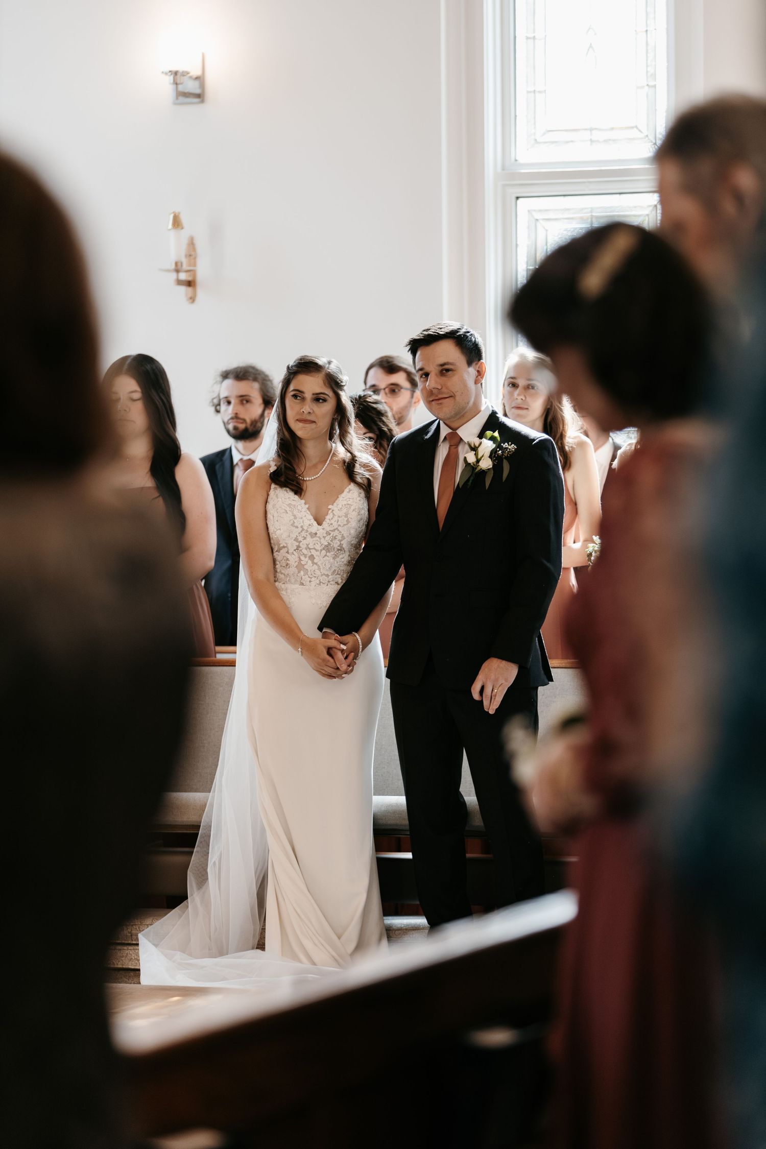 Wedding ceremony participants standing in a traditional church sanctuary.