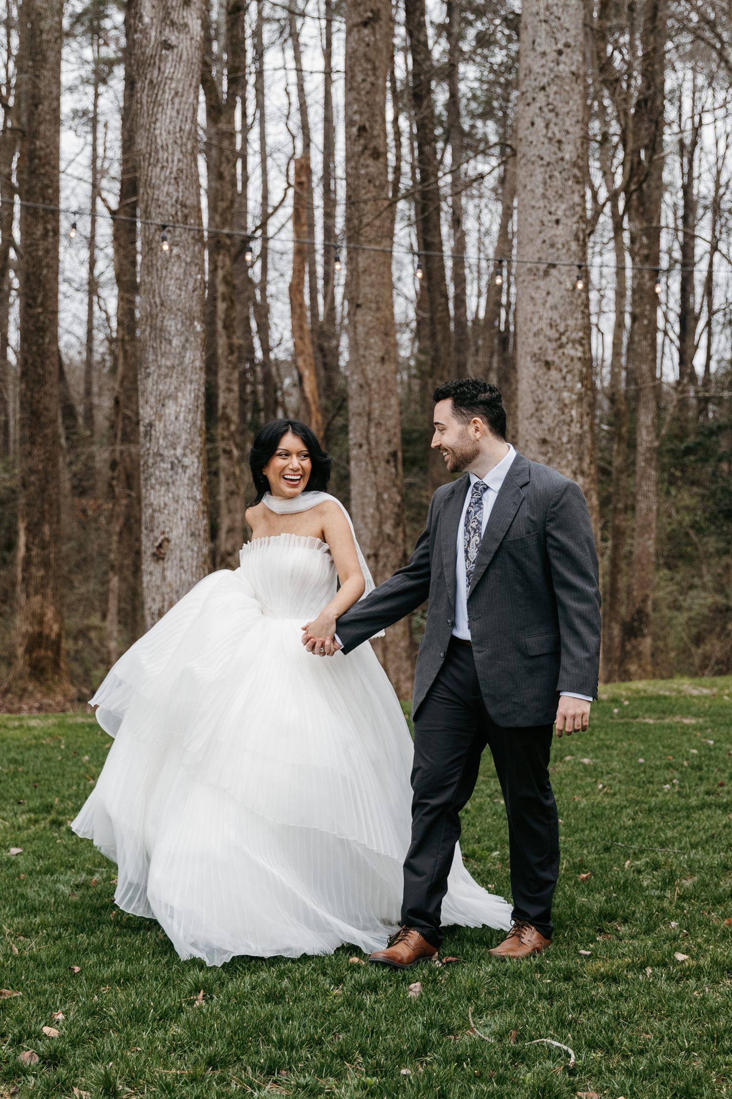 Bride and groom walking  on grass in formal wedding attire.