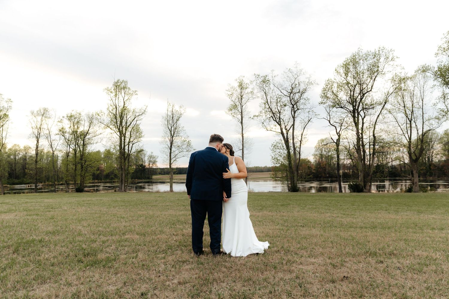 Couple shares intimate moment together in scenic field at sunset.