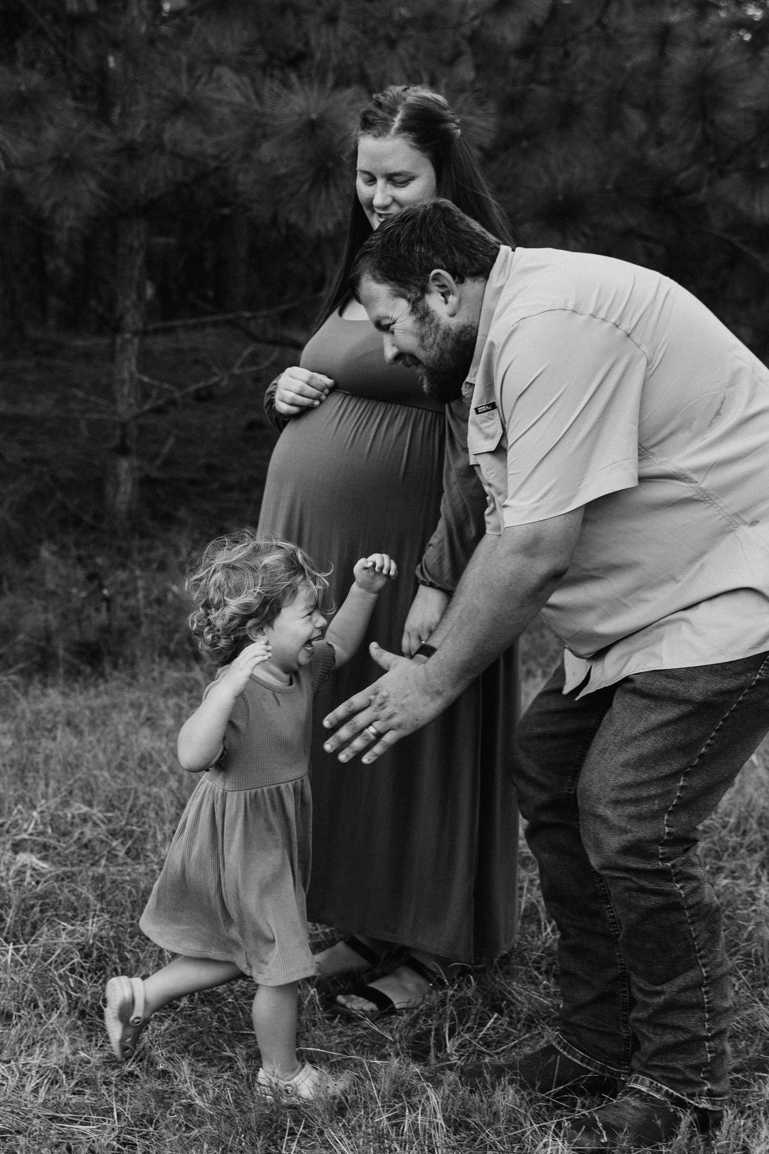 Black and white photo of family sharing a tender moment outdoors.