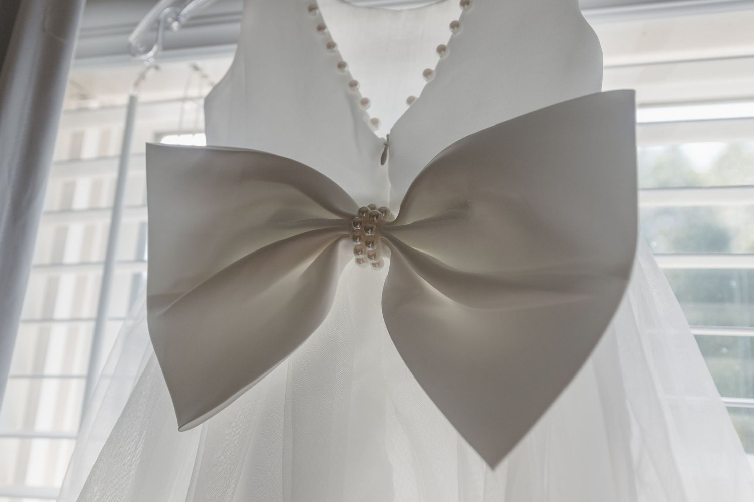 Large decorative white bow detail on wedding attire.