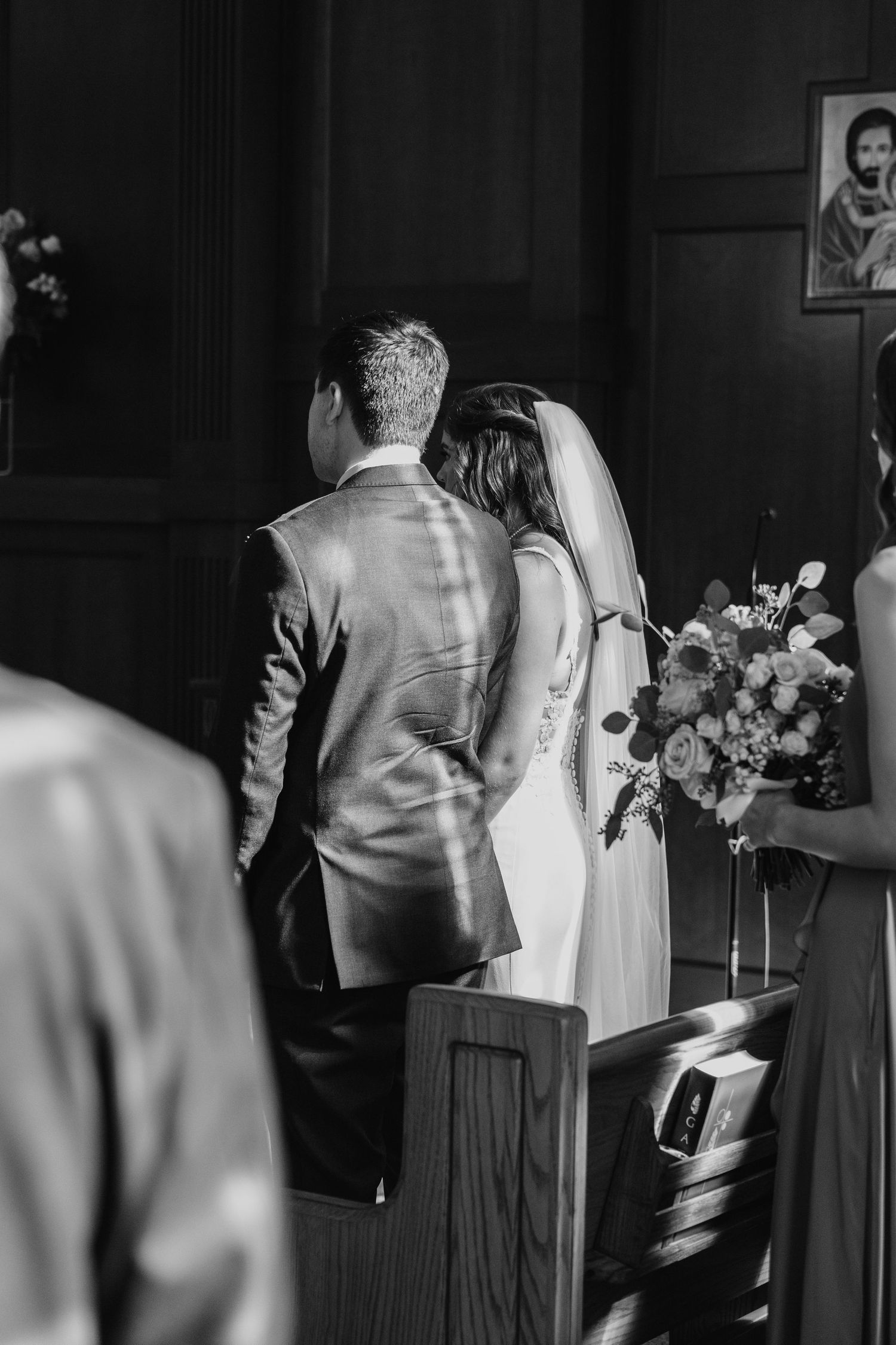 Black and white photo of couple at church altar during wedding ceremony.